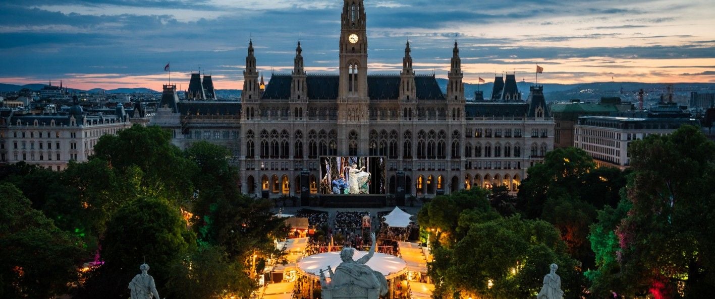 Abendstimmung beim Film Festival vor dem beleuchteten Wiener Rathaus mit Zuschauerbereich.