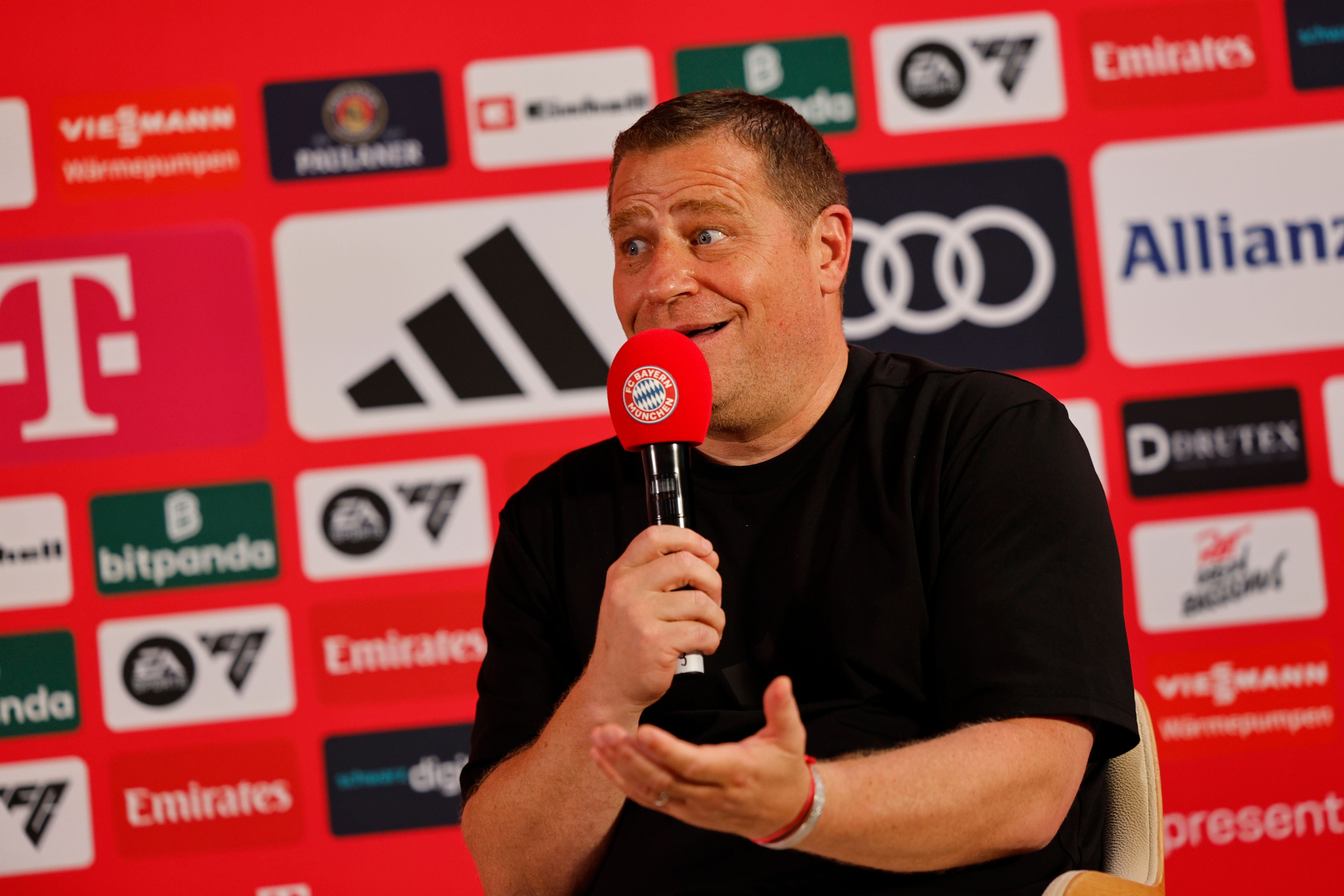 Ein Mann spricht bei einer Pressekonferenz mit rotem FC Bayern Mikrofon vor Sponsorenlogos.