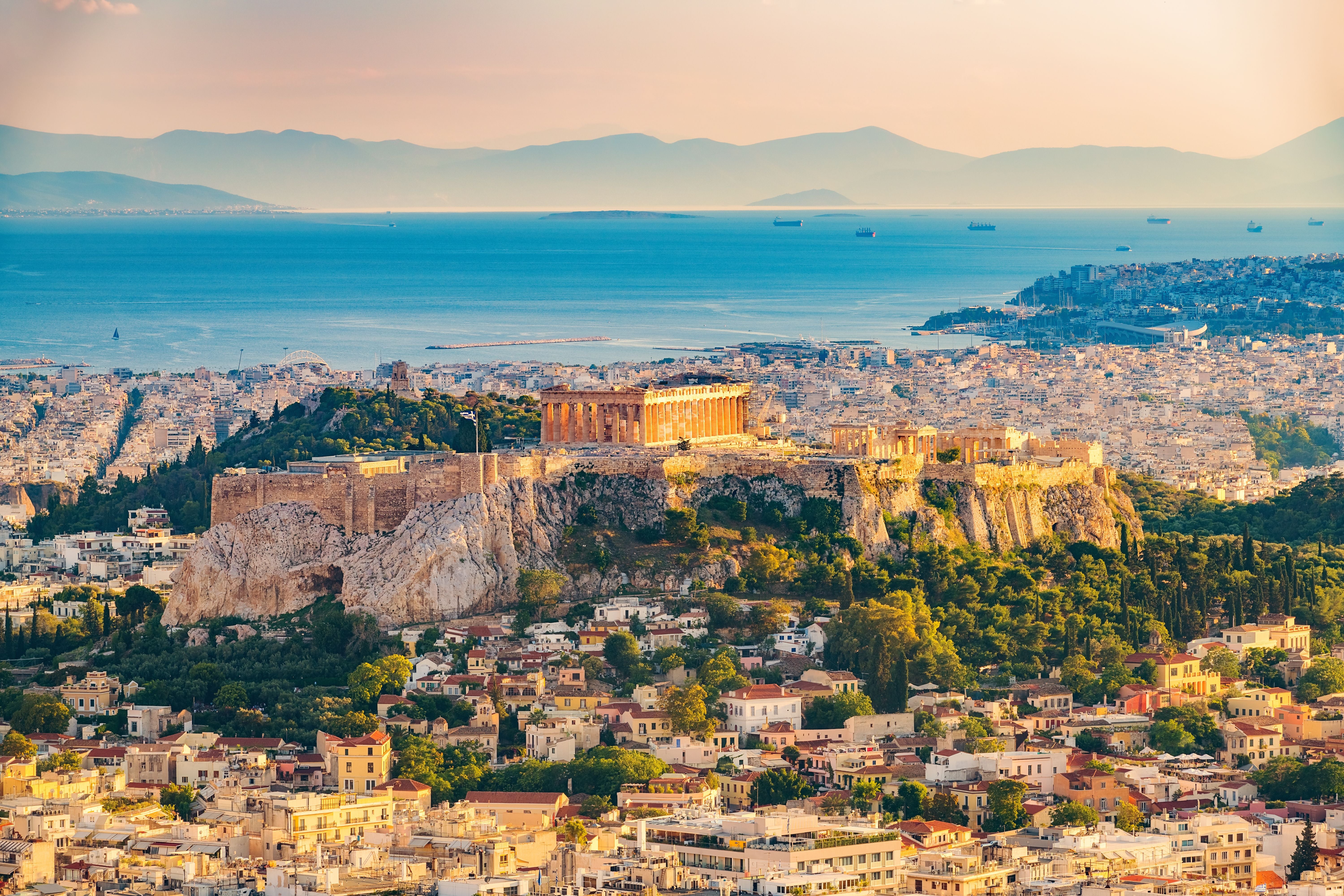 Panoramablick auf Athen mit der Akropolis und dem Meer im Hintergrund bei Sonnenlicht.