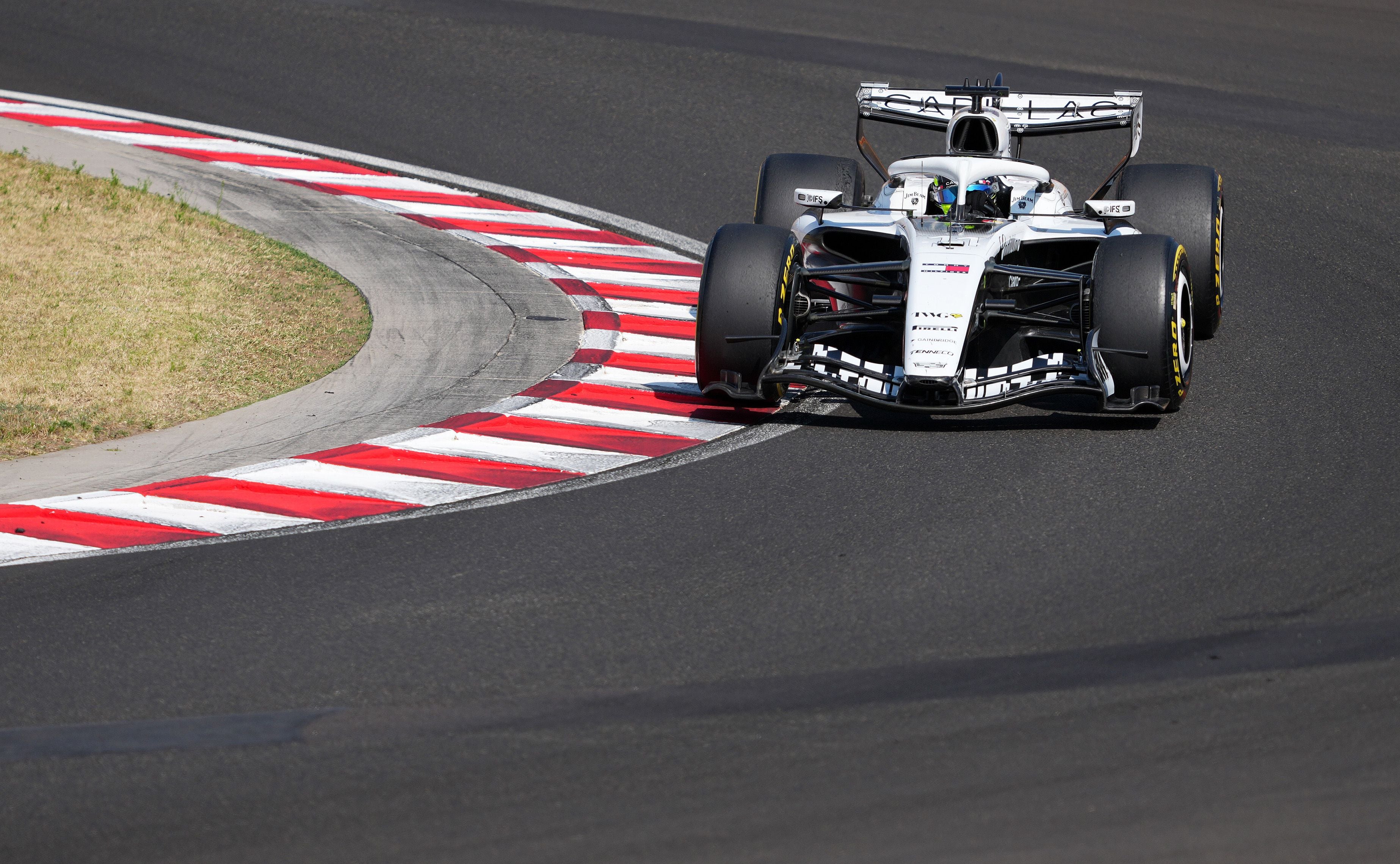 Ein Formel-1-Auto fährt auf einer Rennstrecke durch eine Kurve mit rot-weißen Randsteinen.