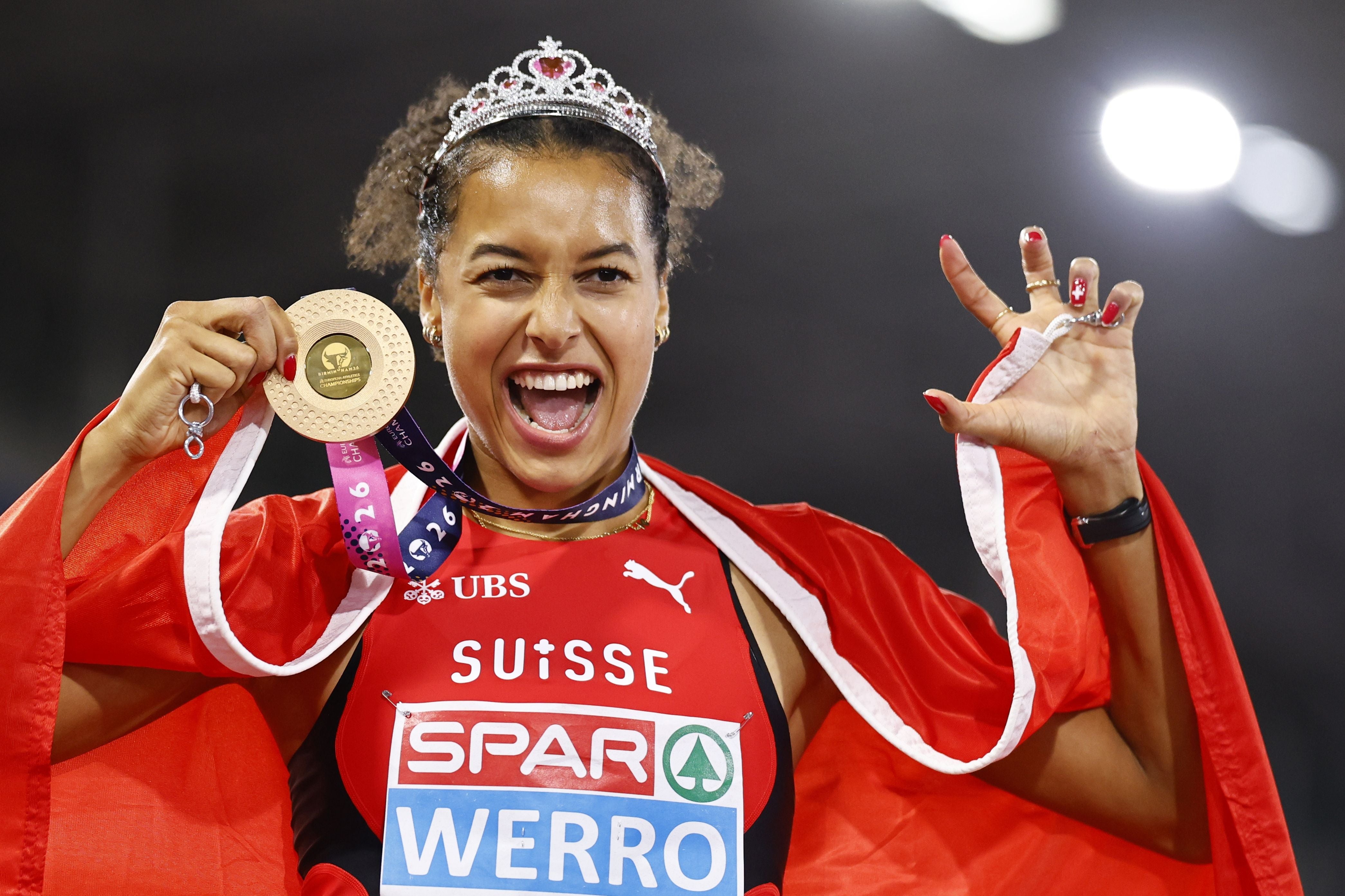 Audrey Werro mit Krone hält ihre Goldmedaille und trägt eine Schweizer Flagge.