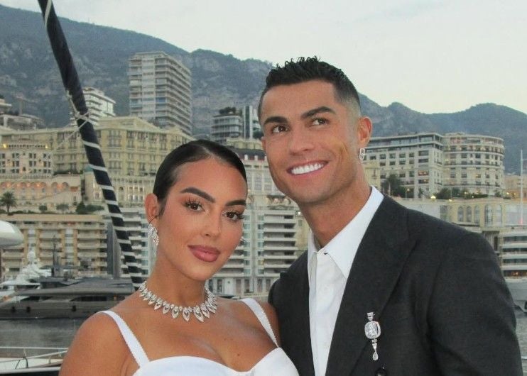 Georgina Rodríguez (32) und Cristiano Ronaldo (41) posieren vor Yachten und Hochhäusern in einer Hafenstadt bei Tageslicht.
