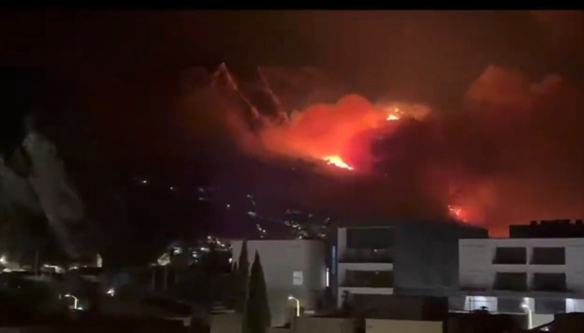Großes Feuer brennt nachts auf einem Hügel in der Nähe von Gebäuden in Kroatien.