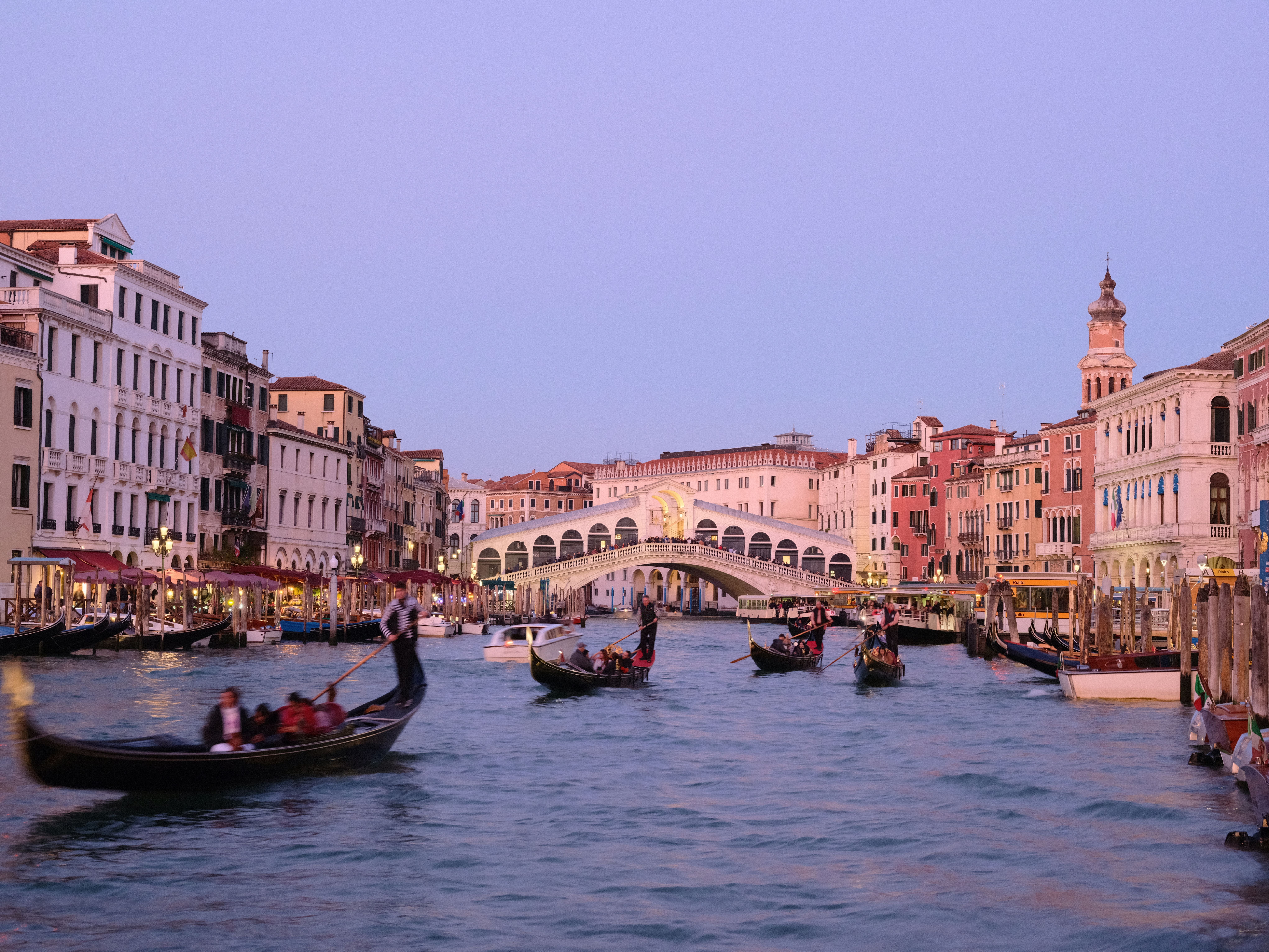 Gondeln fahren auf dem Canal Grande in Venedig, mit der Rialtobrücke im Hintergrund.