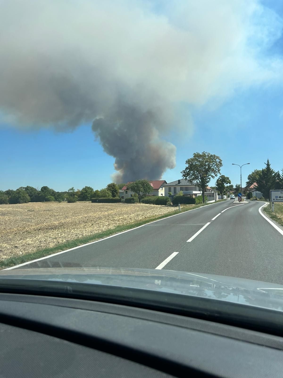 Große Rauchwolke steigt hinter Häusern am Ortsrand von Führenwald in den Himmel auf.
