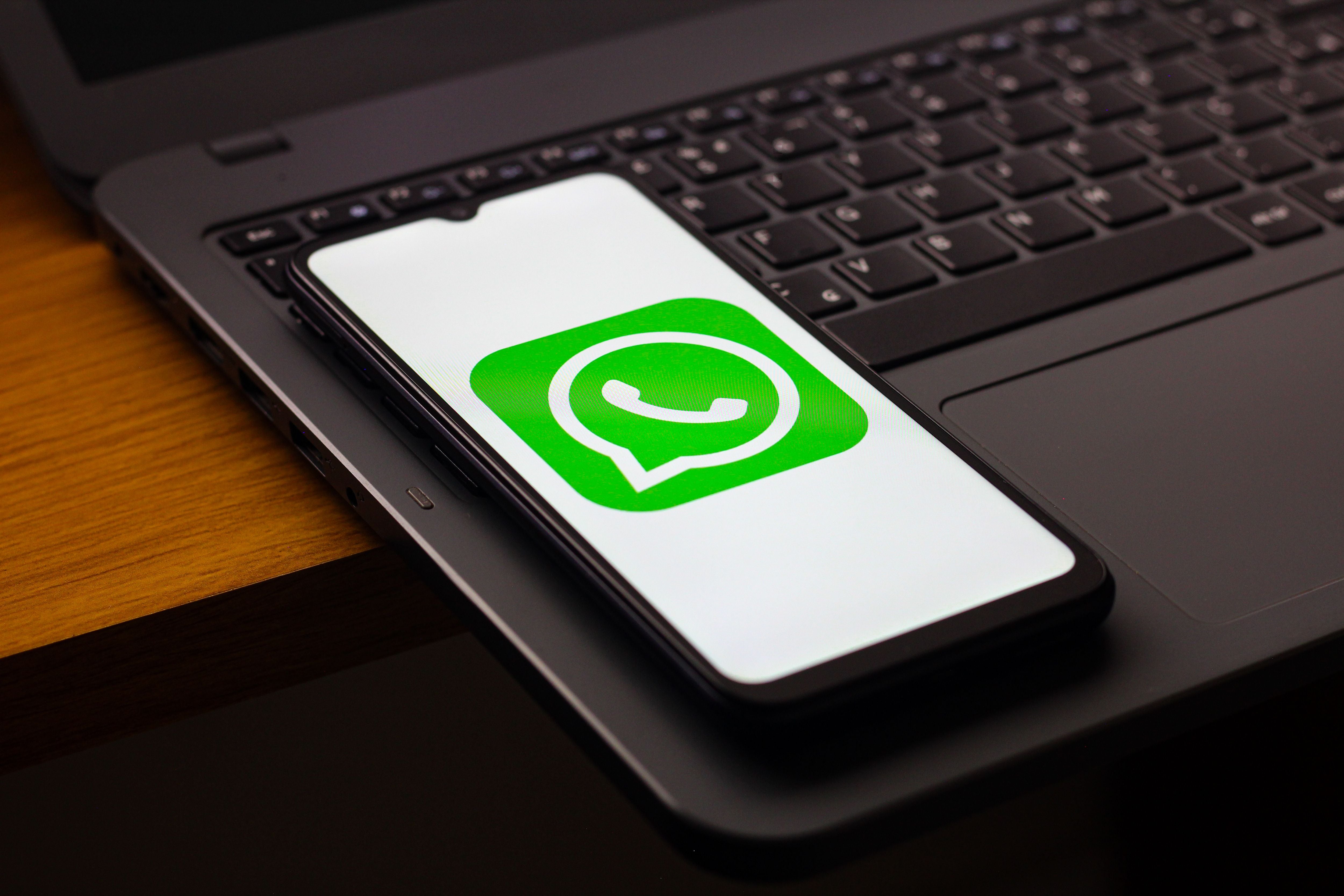 Ein Smartphone mit WhatsApp-Logo liegt auf einer Laptop-Tastatur.