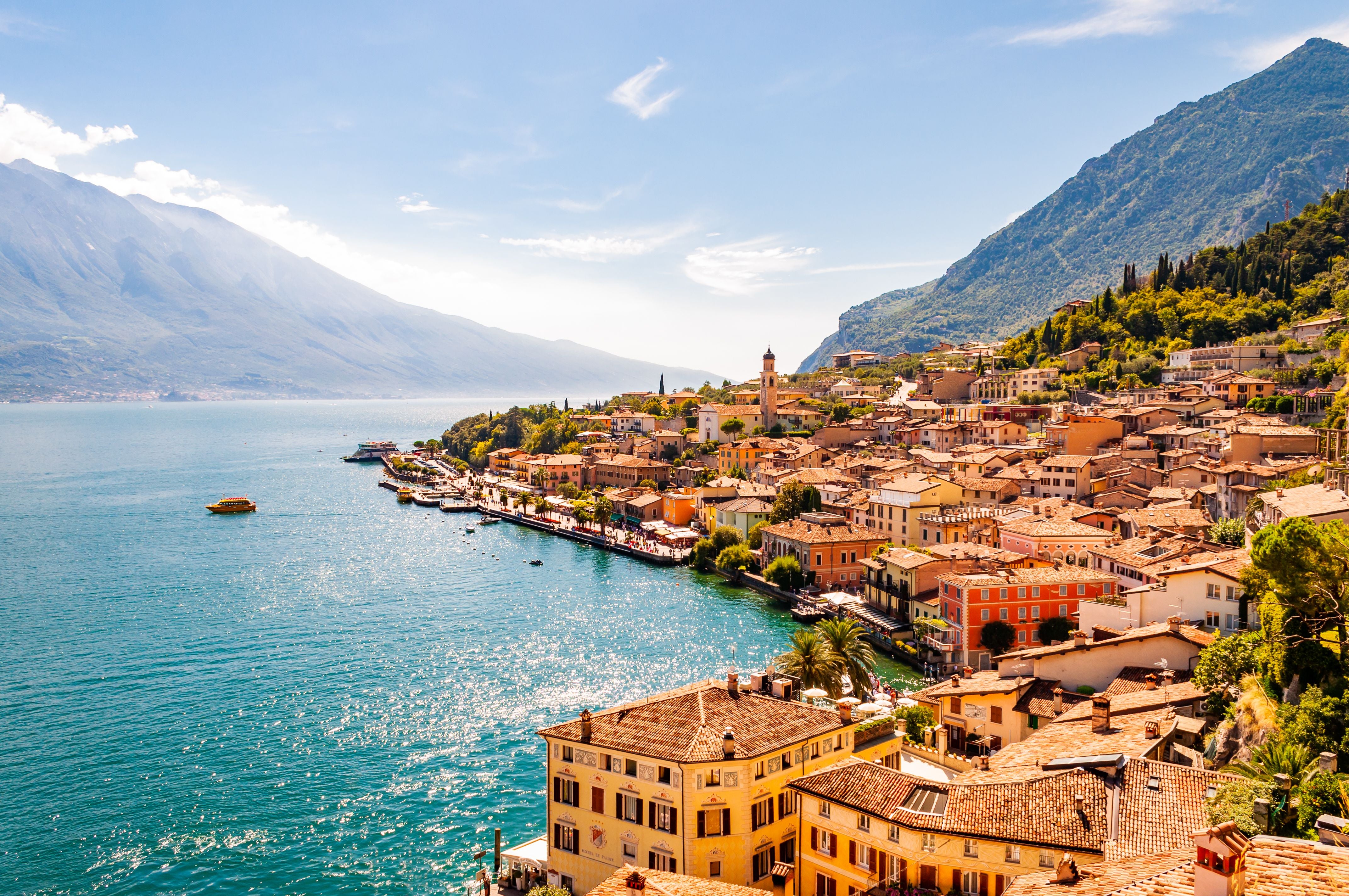 Blick auf Limone Sul Garda mit bunten Häusern am Gardasee und umliegenden Bergen bei sonnigem Wetter.