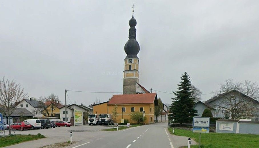 Blick auf eine Kirche mit Zwiebelturm im Ort Mettmach an einer Hauptstraße.
