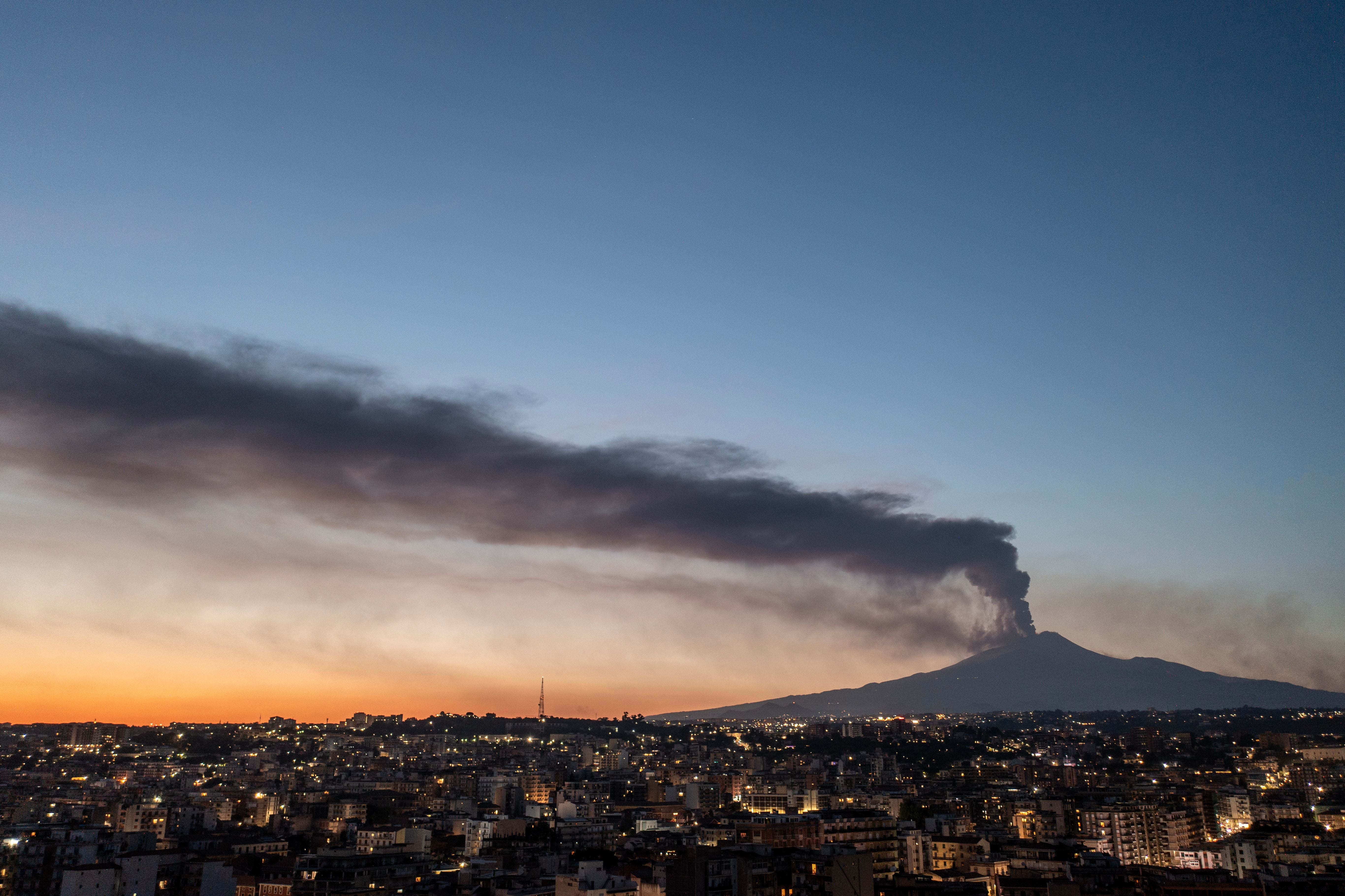 Blick auf Catania bei Abenddämmerung, mit Aschewolke aus dem ausbrechenden Ätna im Hintergrund.