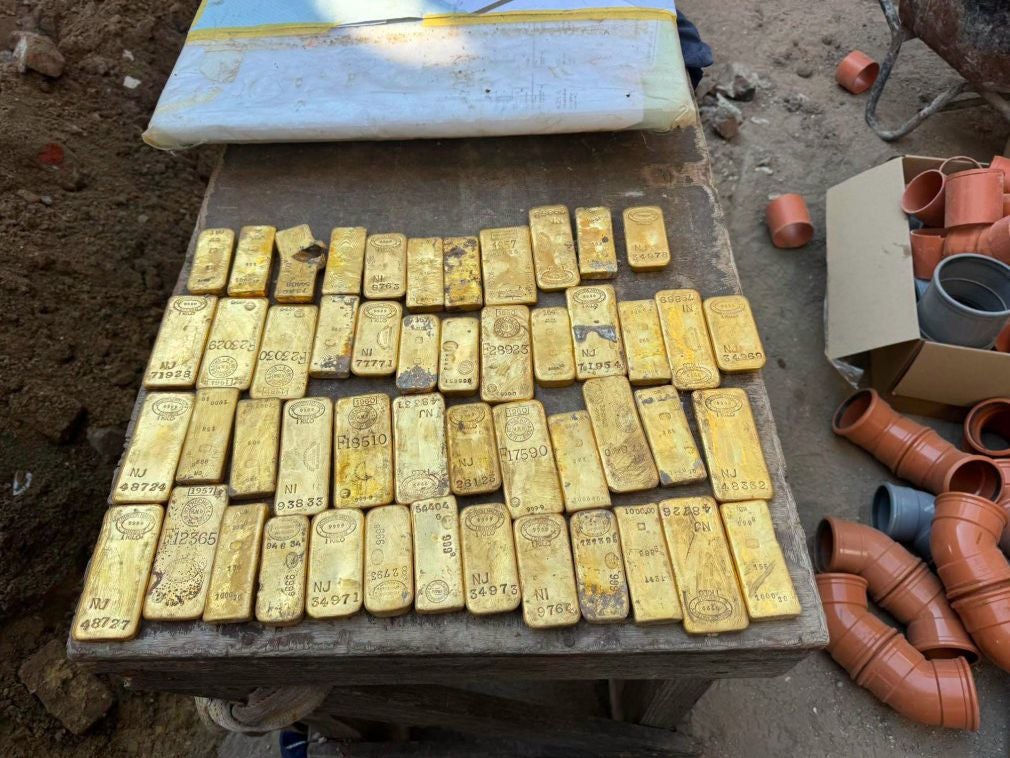Viele Goldbarren liegen nebeneinander auf einem Holztisch an einer Baustelle.