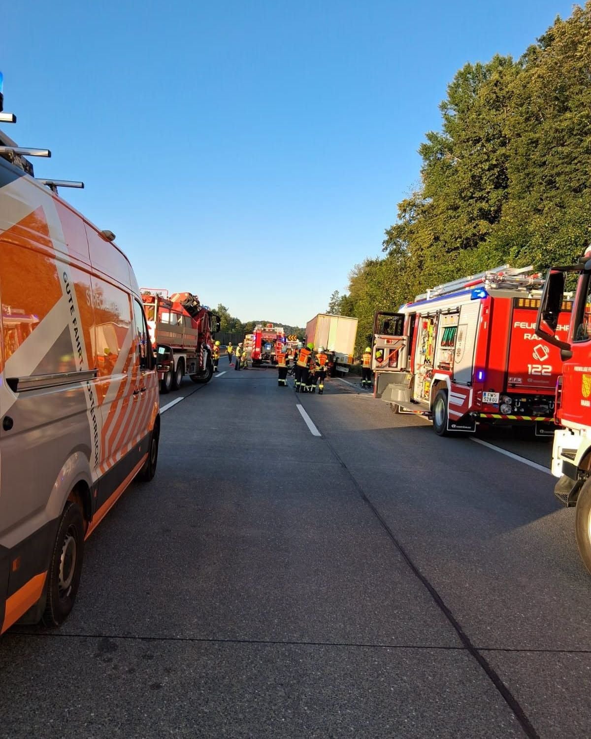Mehrere Einsatzfahrzeuge und Feuerwehrleute auf einer gesperrten Straße bei einem Einsatz.