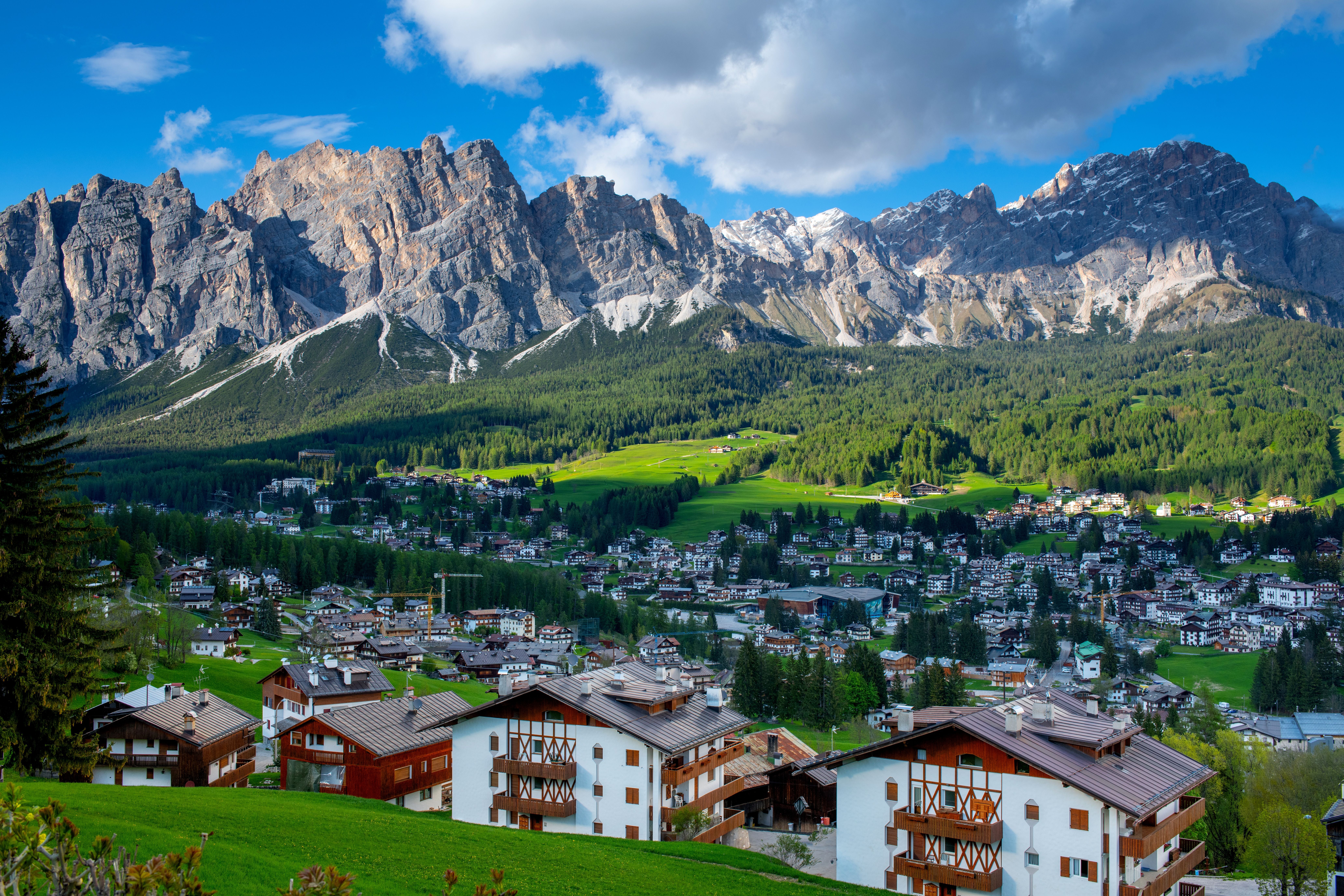 Blick auf Cortina D'Ampezzo mit Häusern und Bergen im Hintergrund bei Sonnenschein.