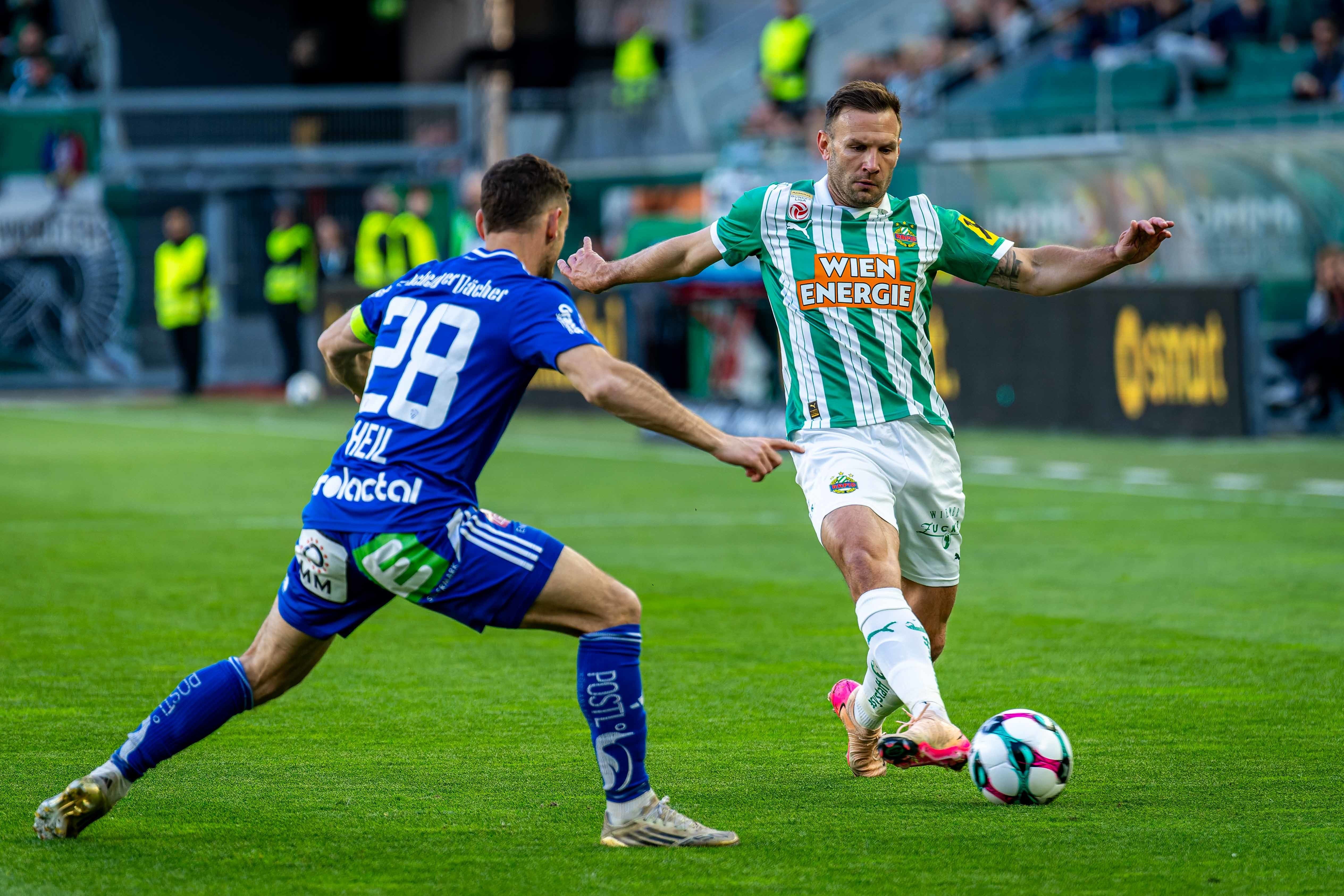Zwei Fußballspieler kämpfen um den Ball während eines Bundesliga-Spiels auf dem Rasen.