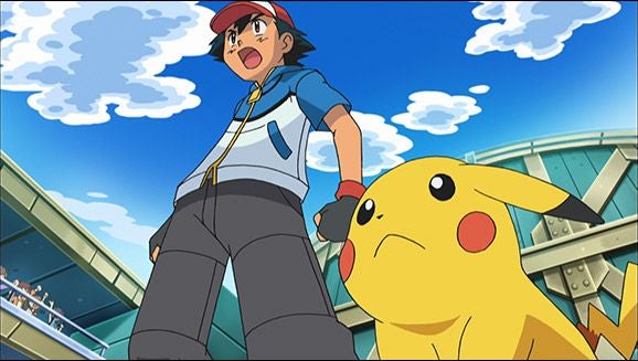Ash und Pikachu stehen nebeneinander in einer Arena mit blauem Himmel im Hintergrund.