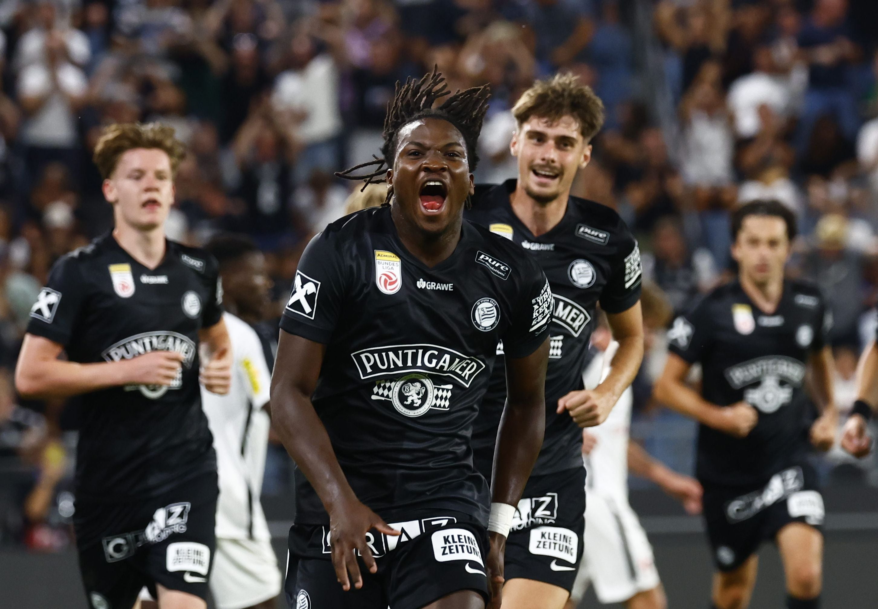 Seedy Jatta jubelt im Trikot von Sturm Graz nach einem Tor, Mitspieler laufen hinter ihm.