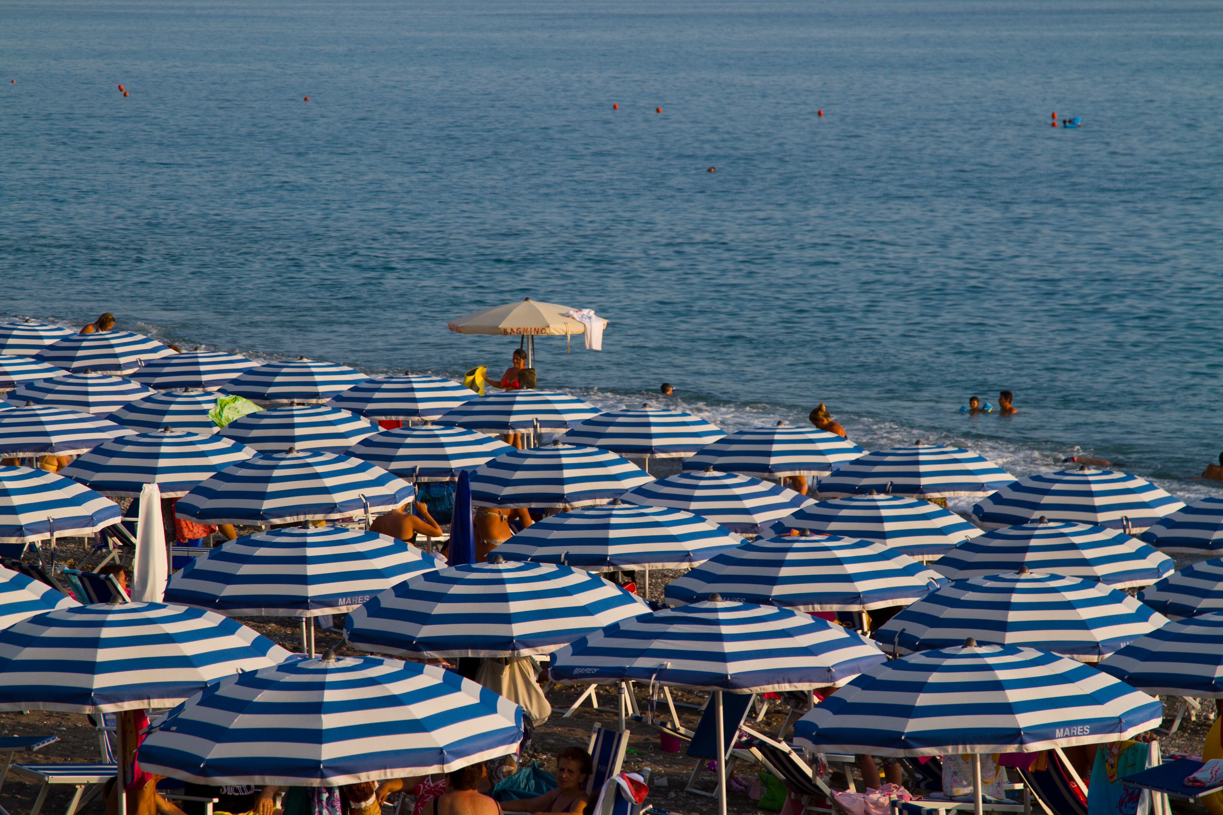 Viele blau-weiß gestreifte Sonnenschirme stehen dicht nebeneinander am Strand von Praia a Mare.