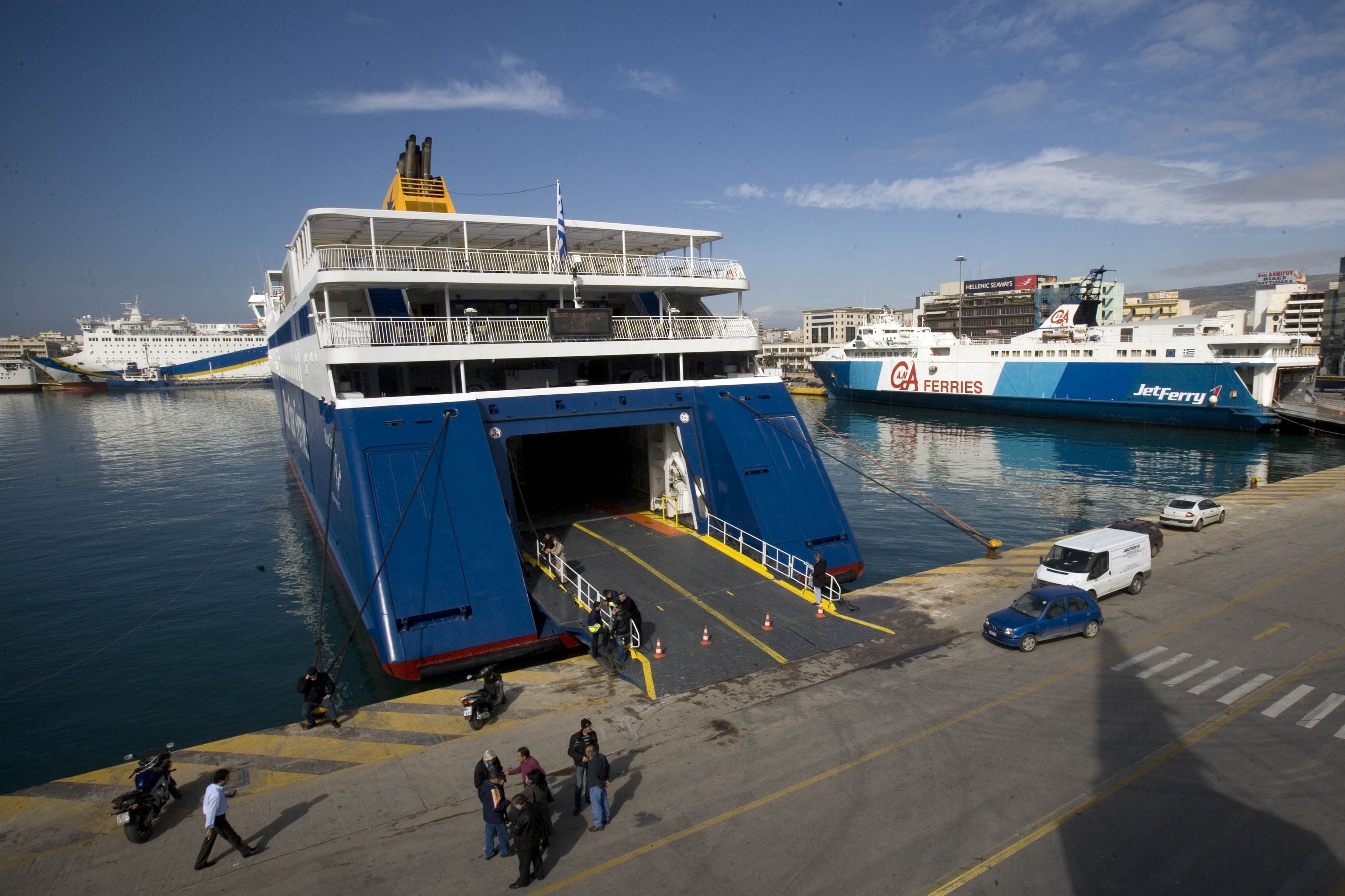 Mehrere Fähren liegen am Hafen von Piräus, mit Menschen und Fahrzeugen am Kai.