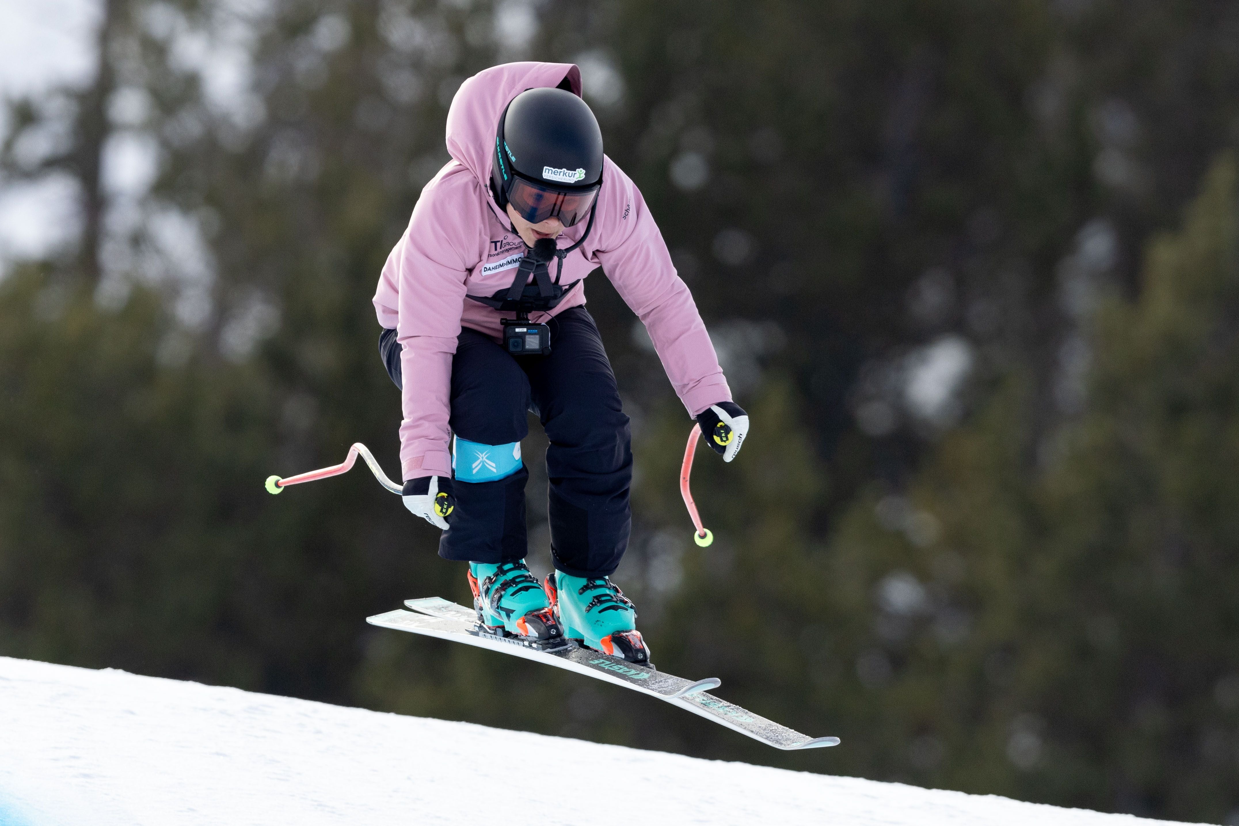 Eine Skifahrerin in pinker Jacke springt beim Super-G über eine Schneekante.