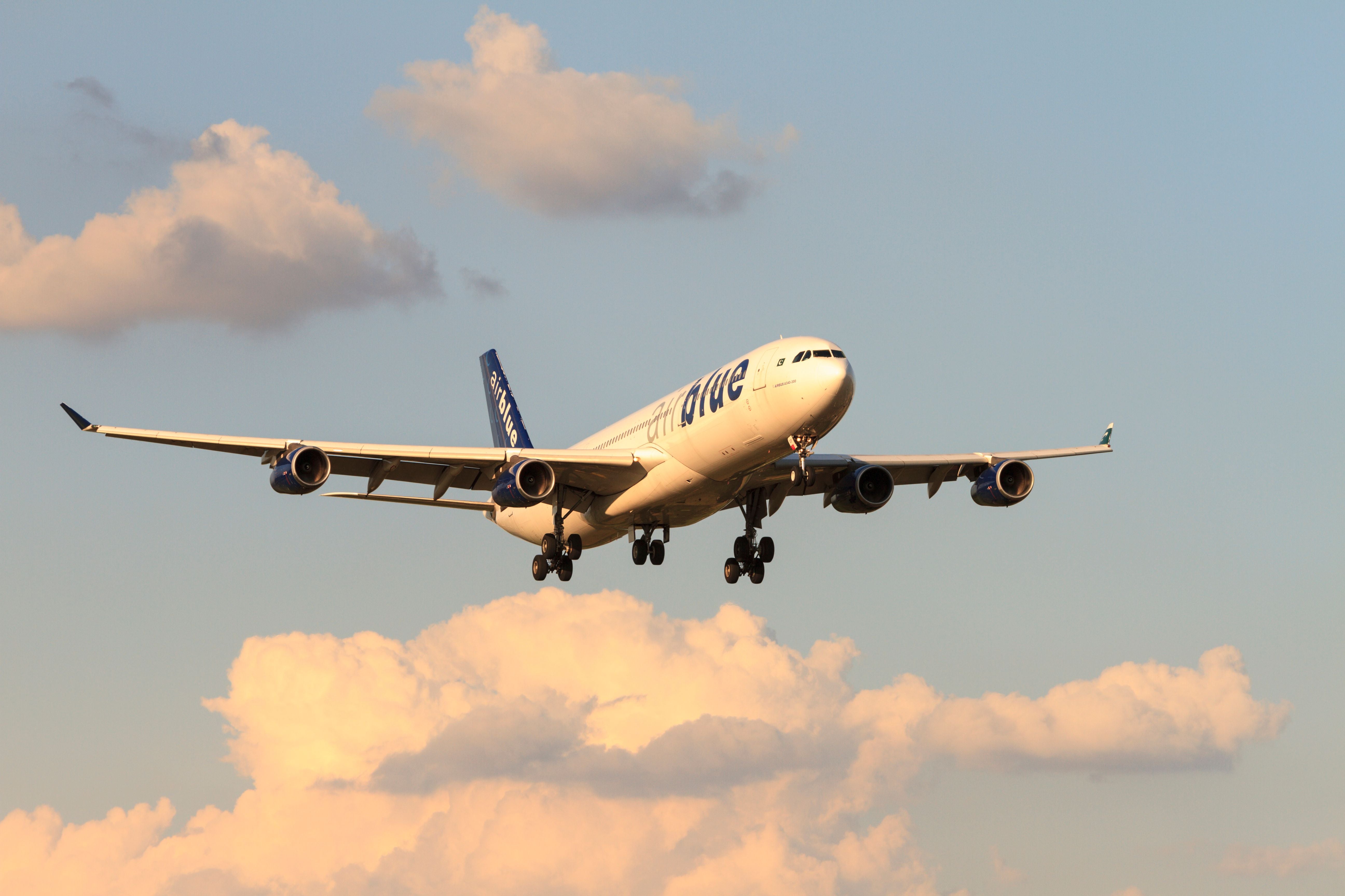Ein Passagierflugzeug fliegt bei Sonnenuntergang durch den Himmel mit wolkigem Hintergrund.