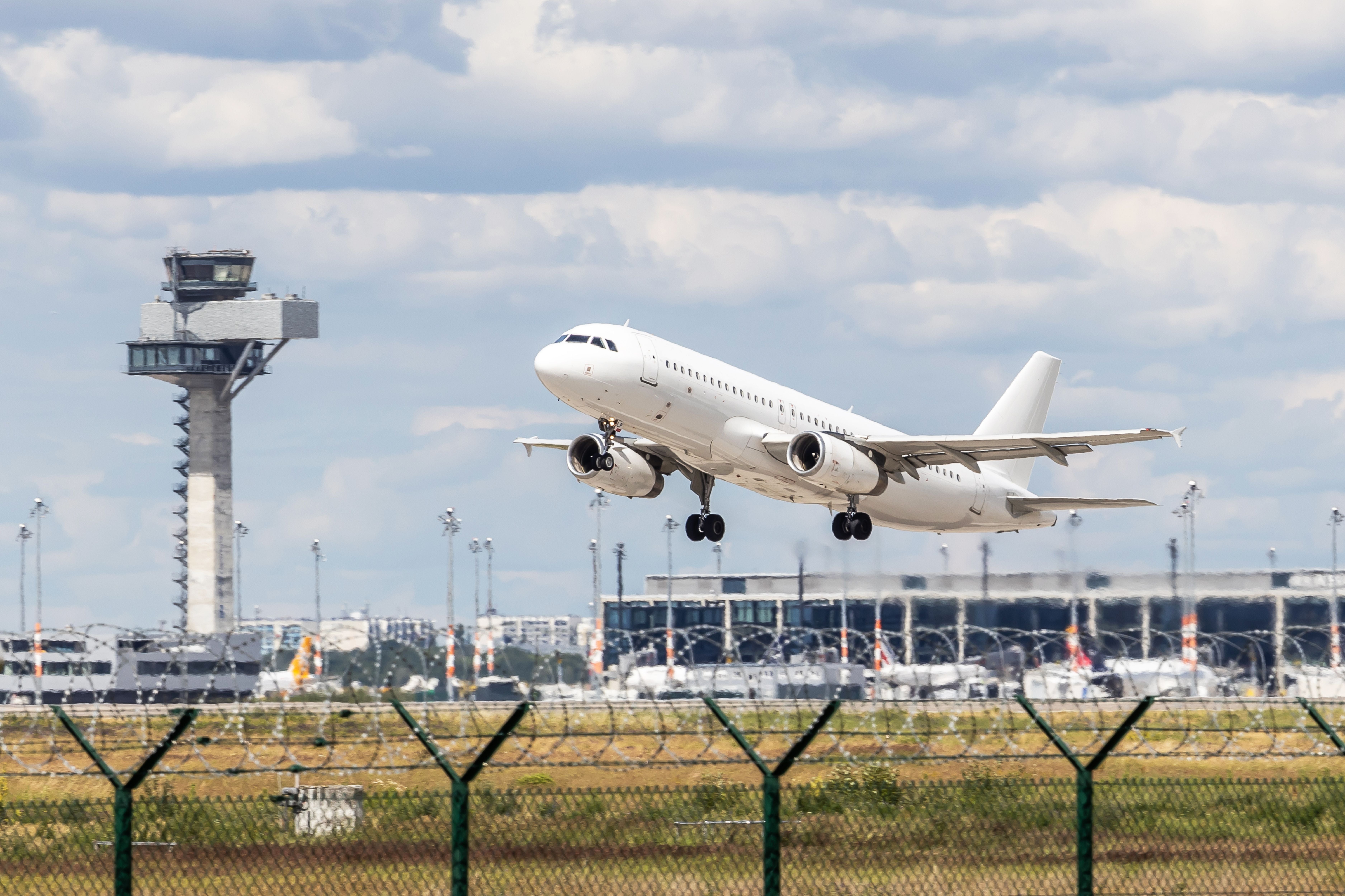 Ein Flugzeug startet am Flughafen BER, im Hintergrund sind Tower und Terminal zu sehen.
