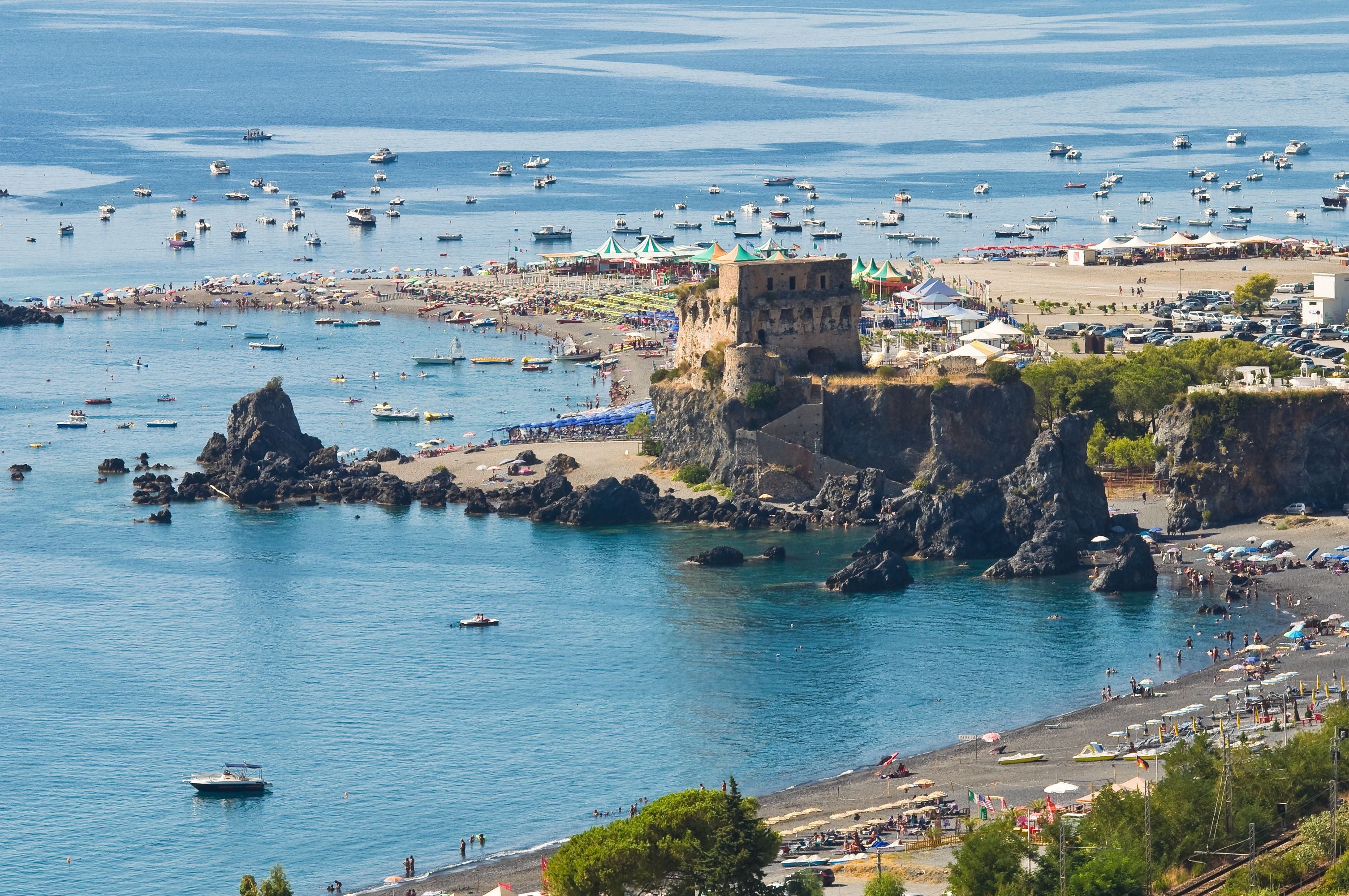 Blick auf den Torre di Fiuzzi am Strand von Praia a Mare mit vielen Booten und Badegästen.