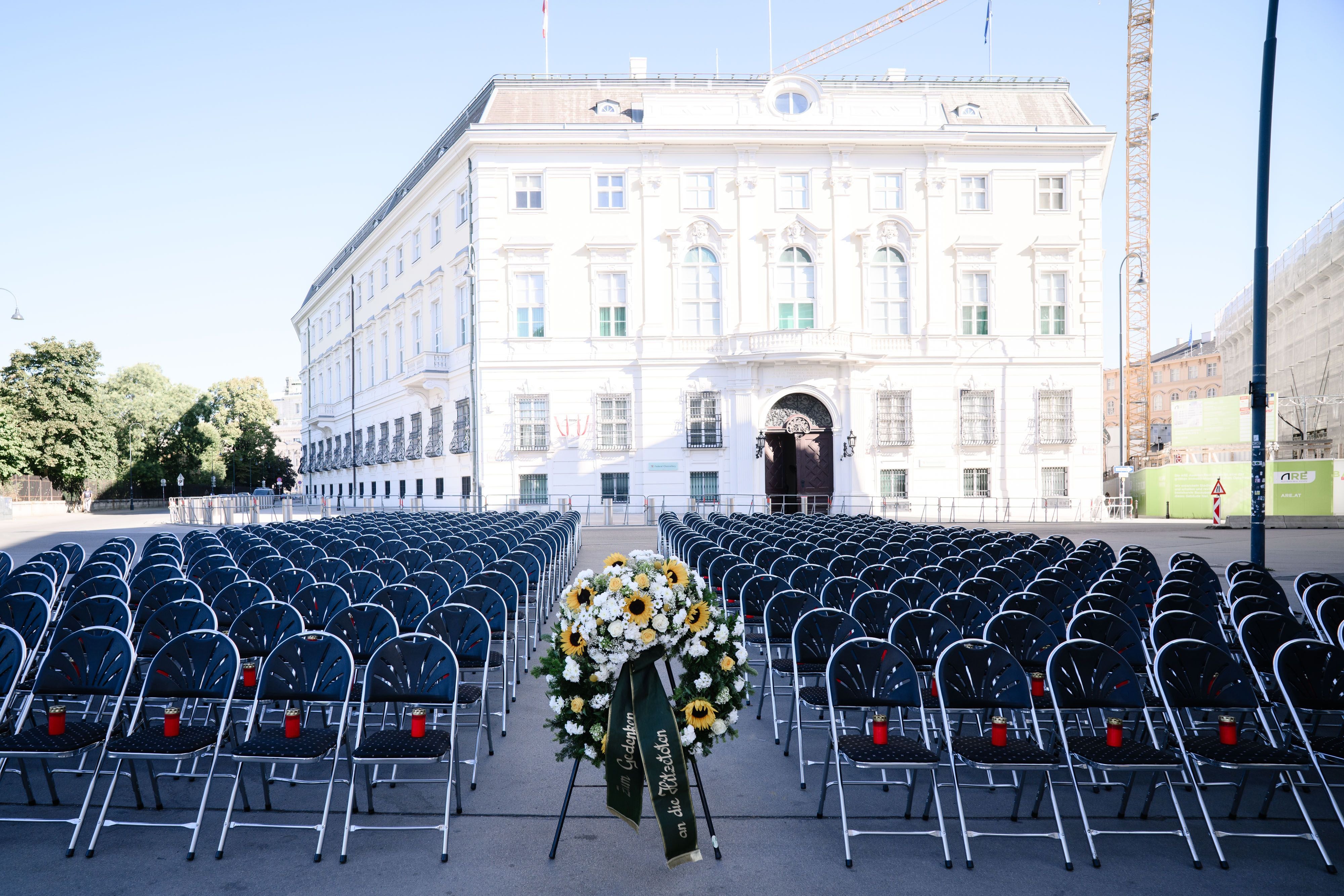 Vor dem Bundeskanzleramt Wien stehen viele leere Stühle mit Kerzen und einem Trauerkranz.