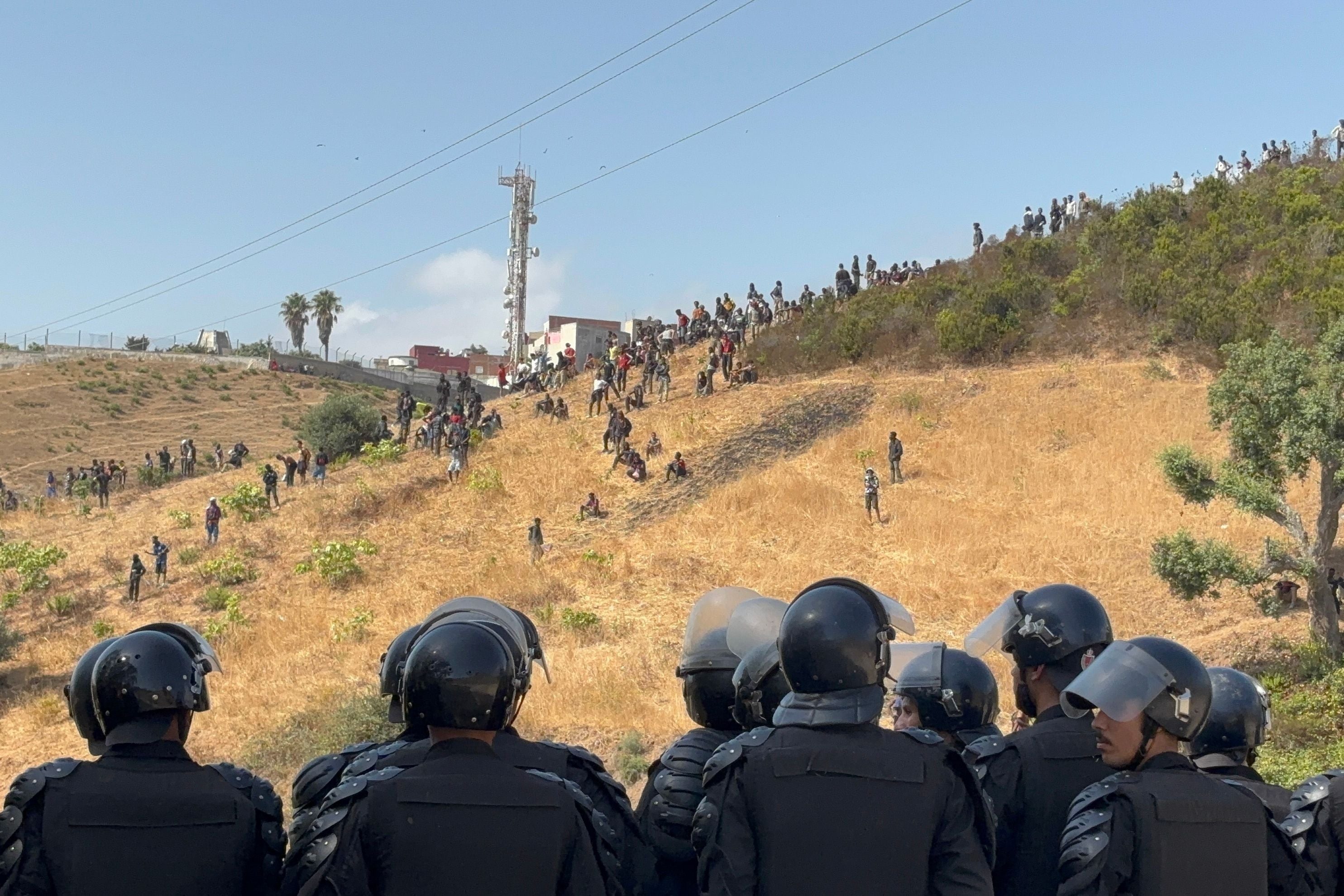 Marokkanische Polizisten beobachten Migranten auf einem Hügel nahe Castillejos.