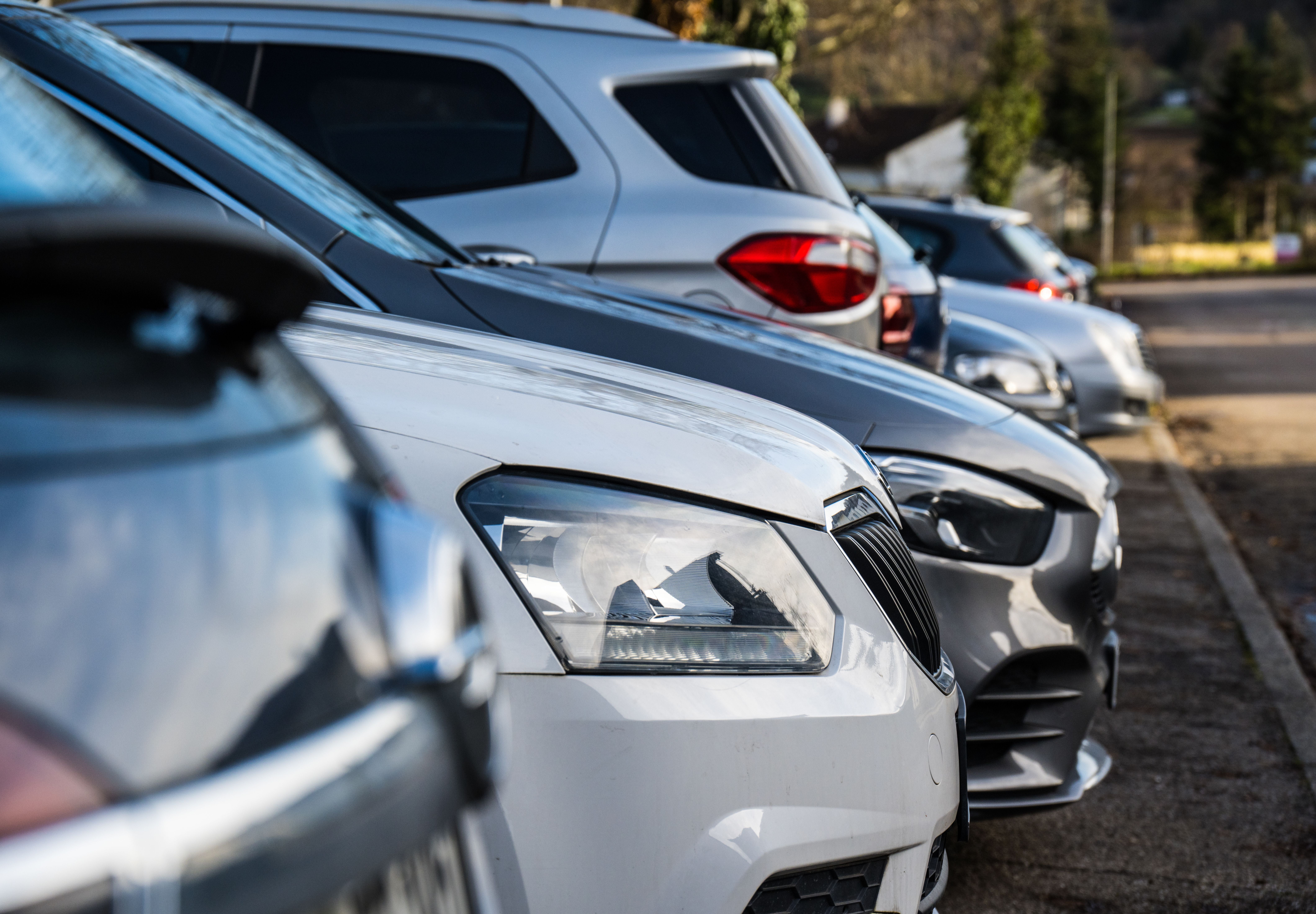 Mehrere Autos parken dicht nebeneinander auf einem Parkplatz am Straßenrand.