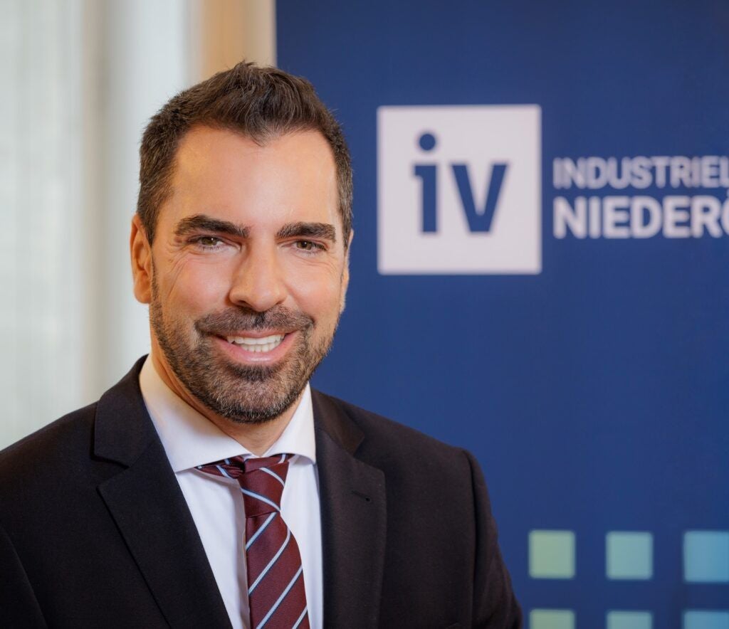 Mann im Anzug vor einem blauem Hintergrund mit IV Niederösterreich Logo.