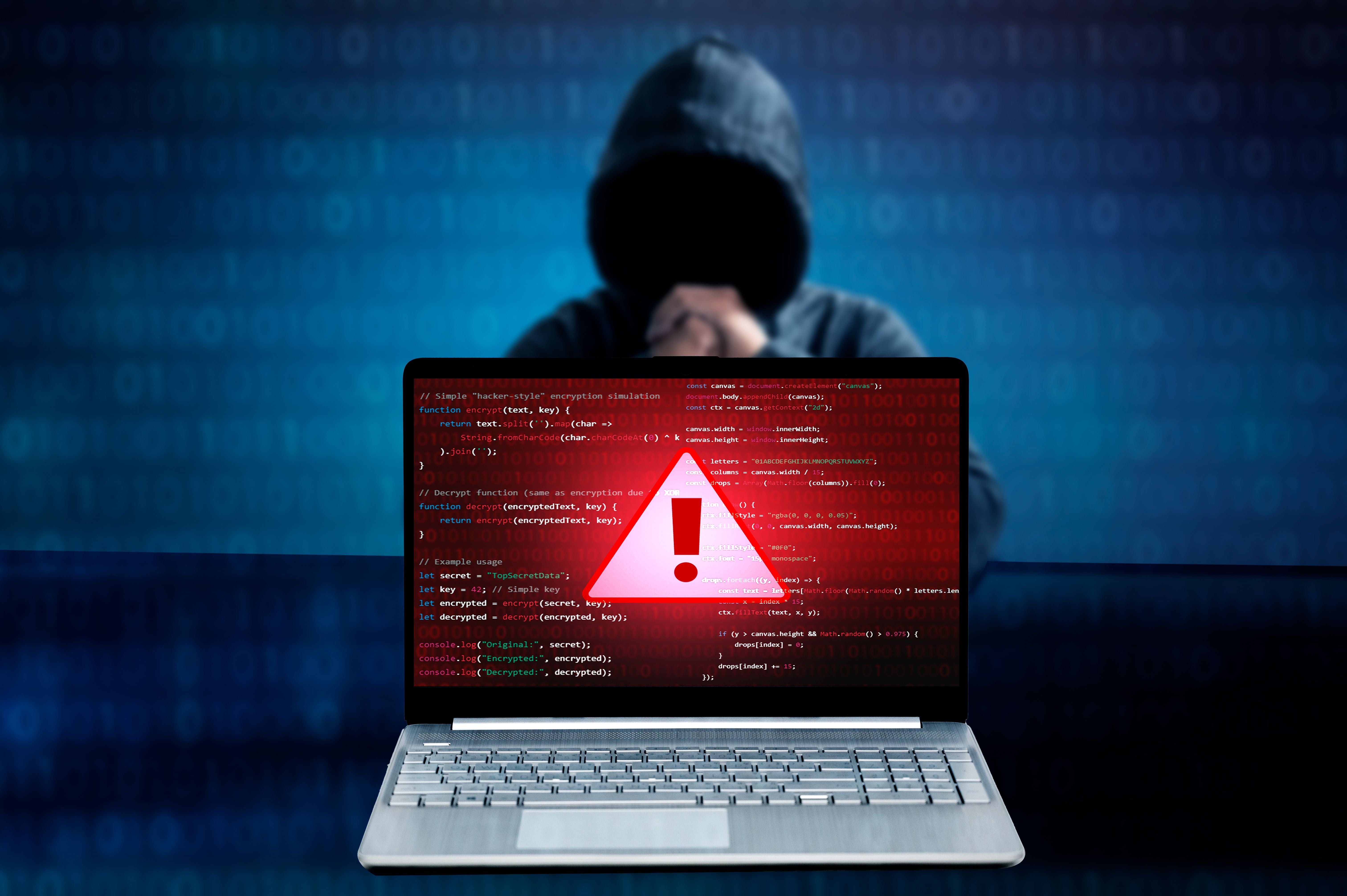 Laptop mit Warnsymbol auf dem Bildschirm, im Hintergrund eine Person mit Kapuze, Symbol für Cyberangriff.