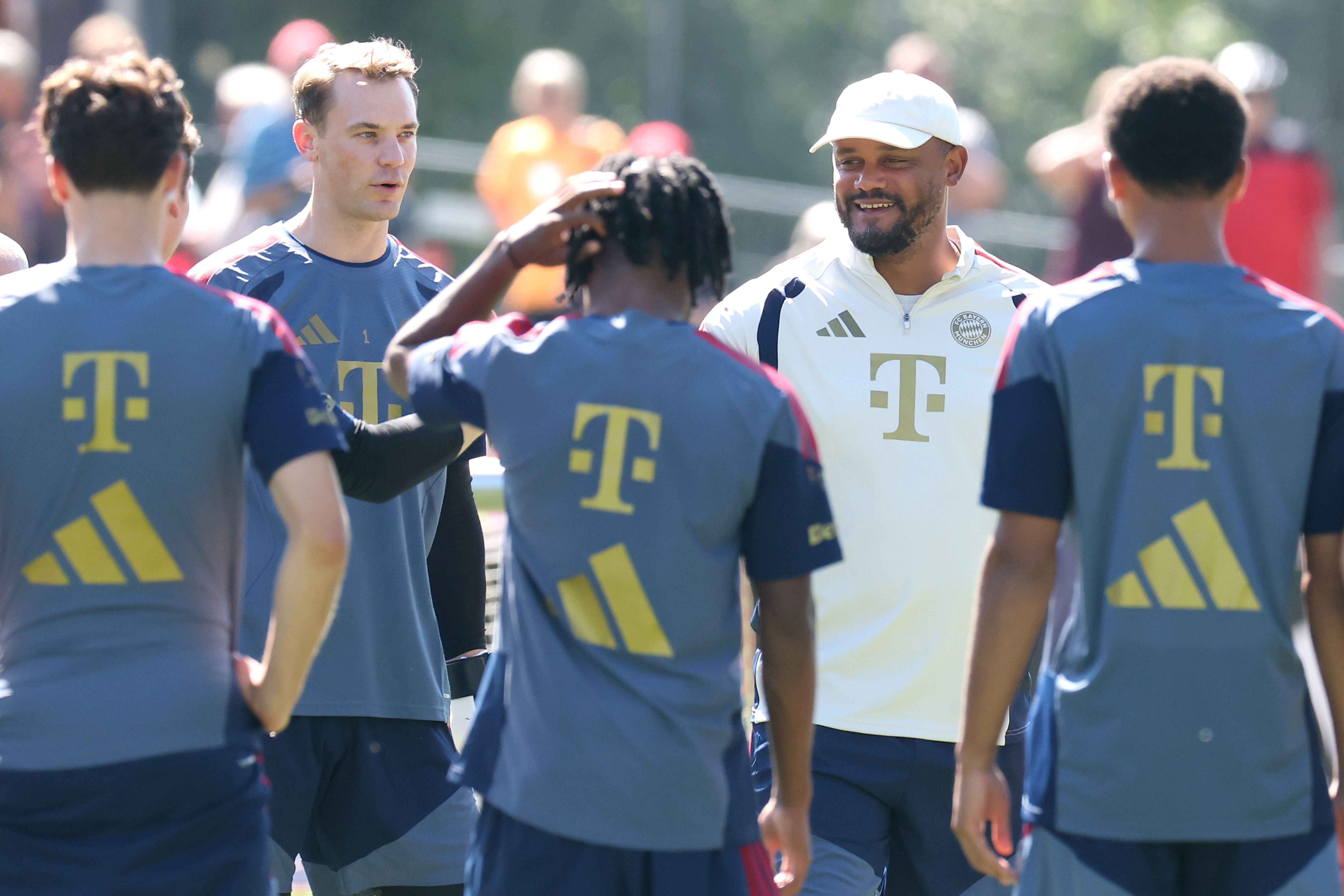 Trainer und Spieler des FC Bayern München sprechen miteinander beim Training im Freien.