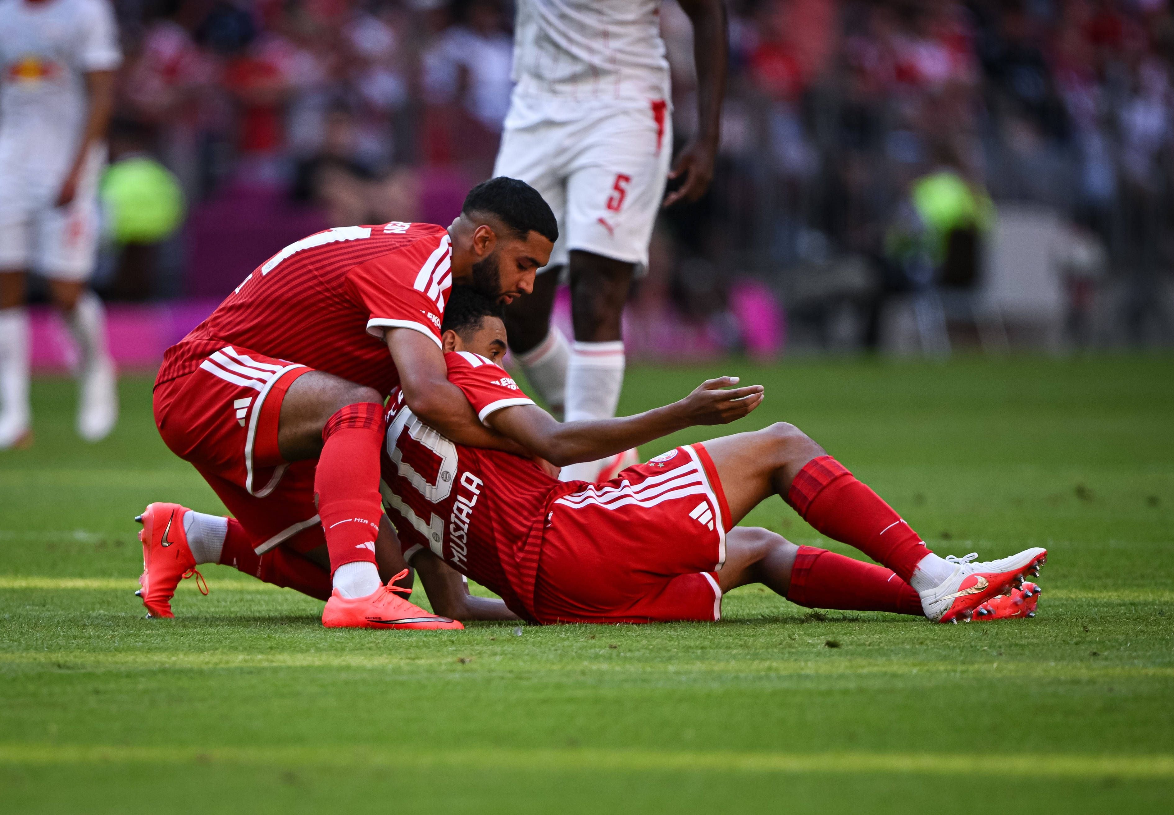 Zwei Bayern-Spieler in roten Trikots feiern ein Tor am Boden auf dem Fußballfeld.