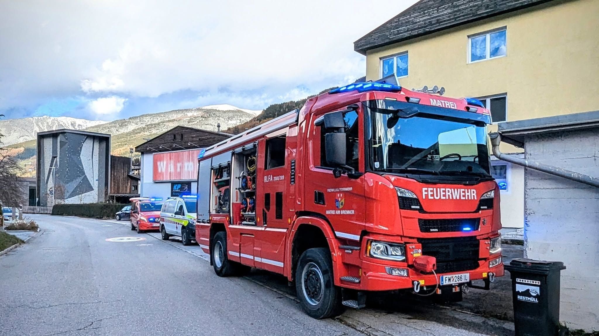 Ein rotes Feuerwehrfahrzeug der Feuerwehr Matrei steht mit Blaulicht am Straßenrand.