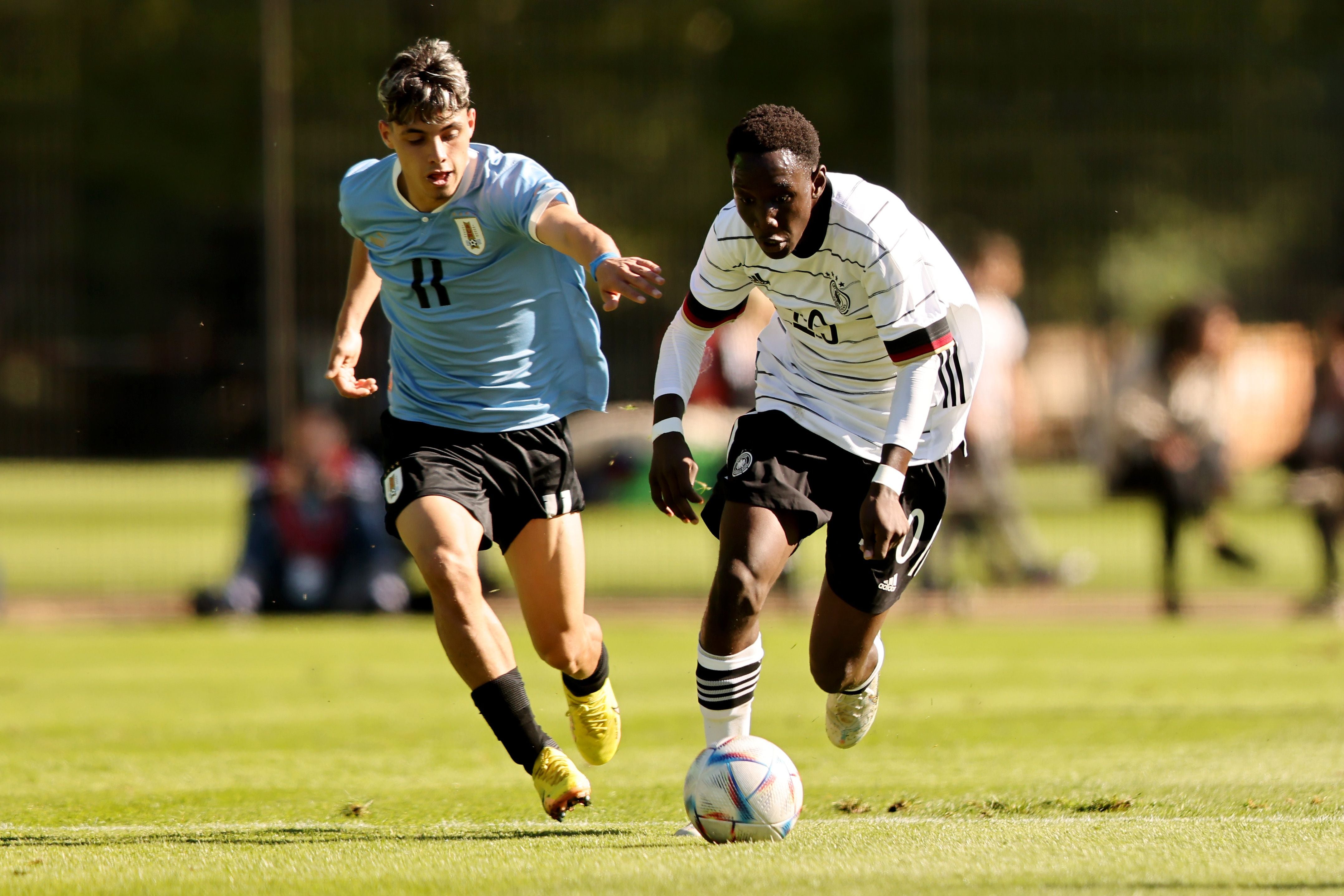 Ein deutscher und ein uruguayischer U17-Fußballspieler kämpfen um den Ball auf dem Spielfeld.