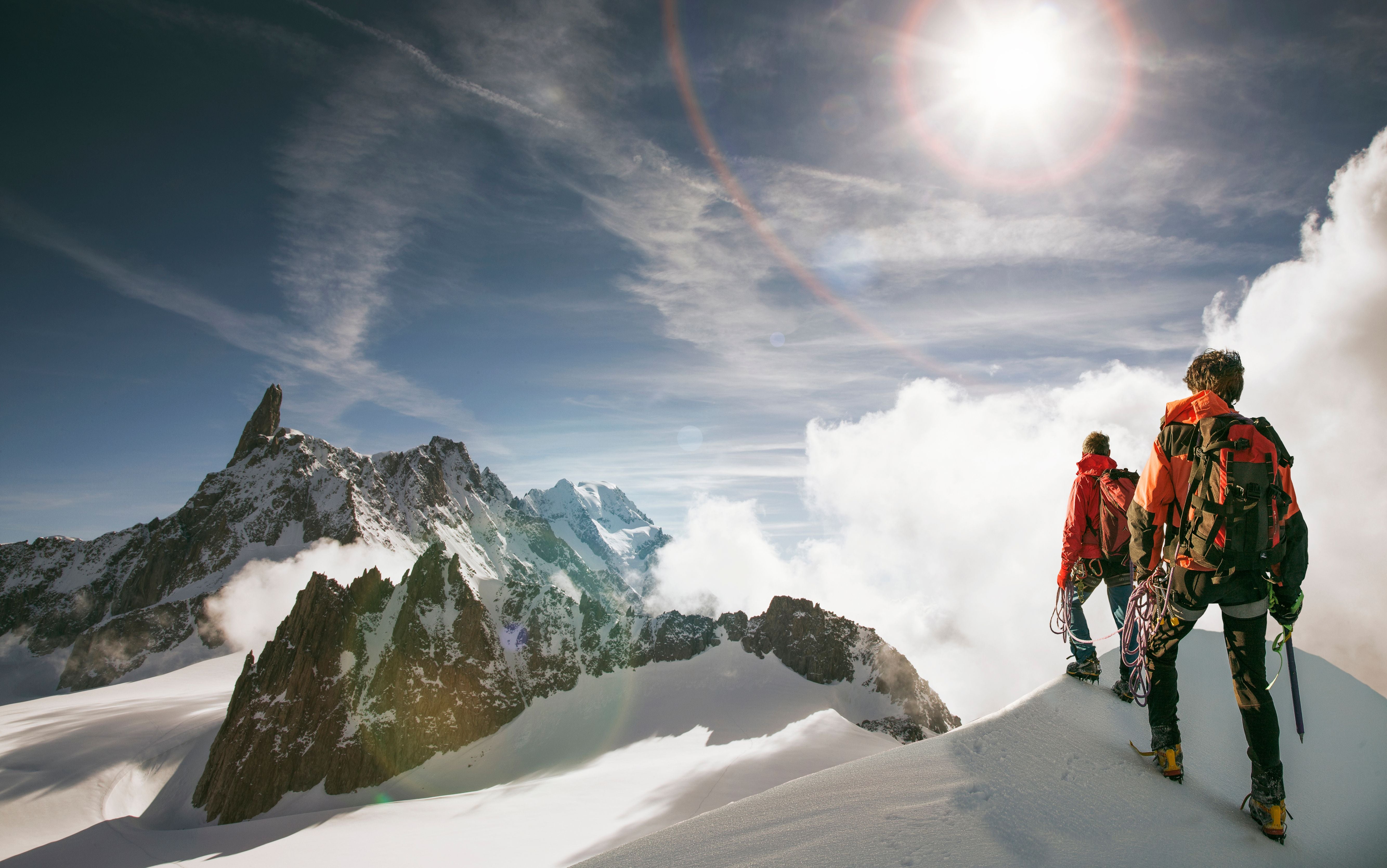 Zwei Bergsteiger wandern auf einem verschneiten Grat am Mont Blanc bei Sonnenschein.