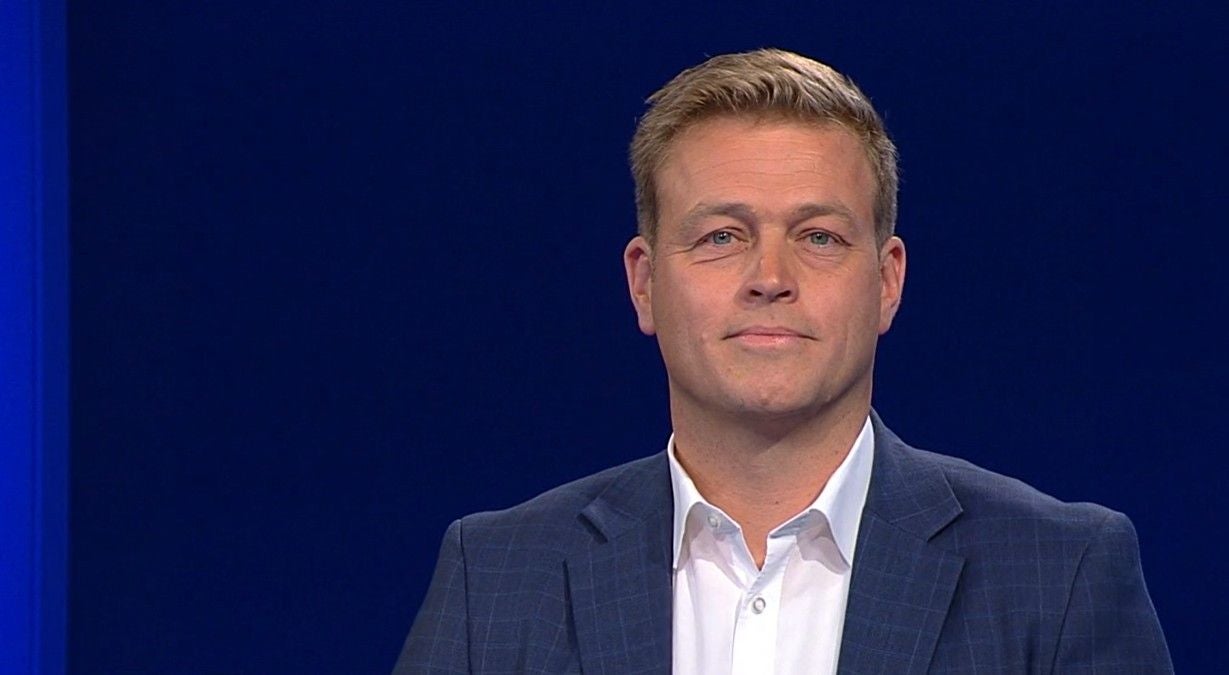 Mann in Anzug vor dunkelblauem Hintergrund, Blick in die Kamera.