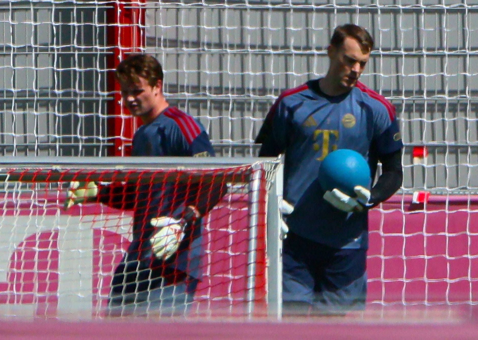 Zwei Torhüter vom FC Bayern trainieren am Tor, einer hält einen blauen Ball.