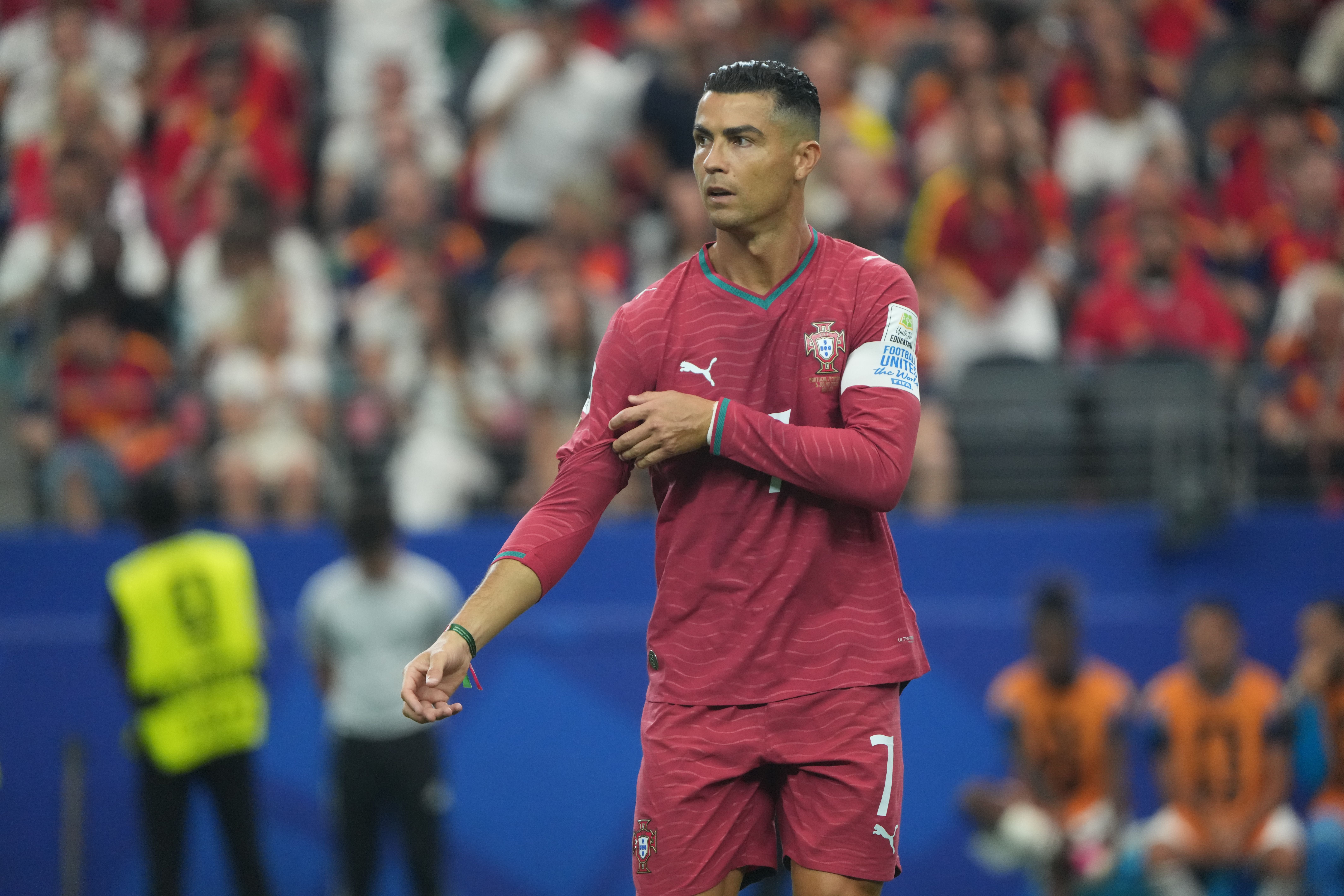 Ein portugiesischer Fußballspieler im roten Trikot blickt während eines Spiels konzentriert zur Seite.