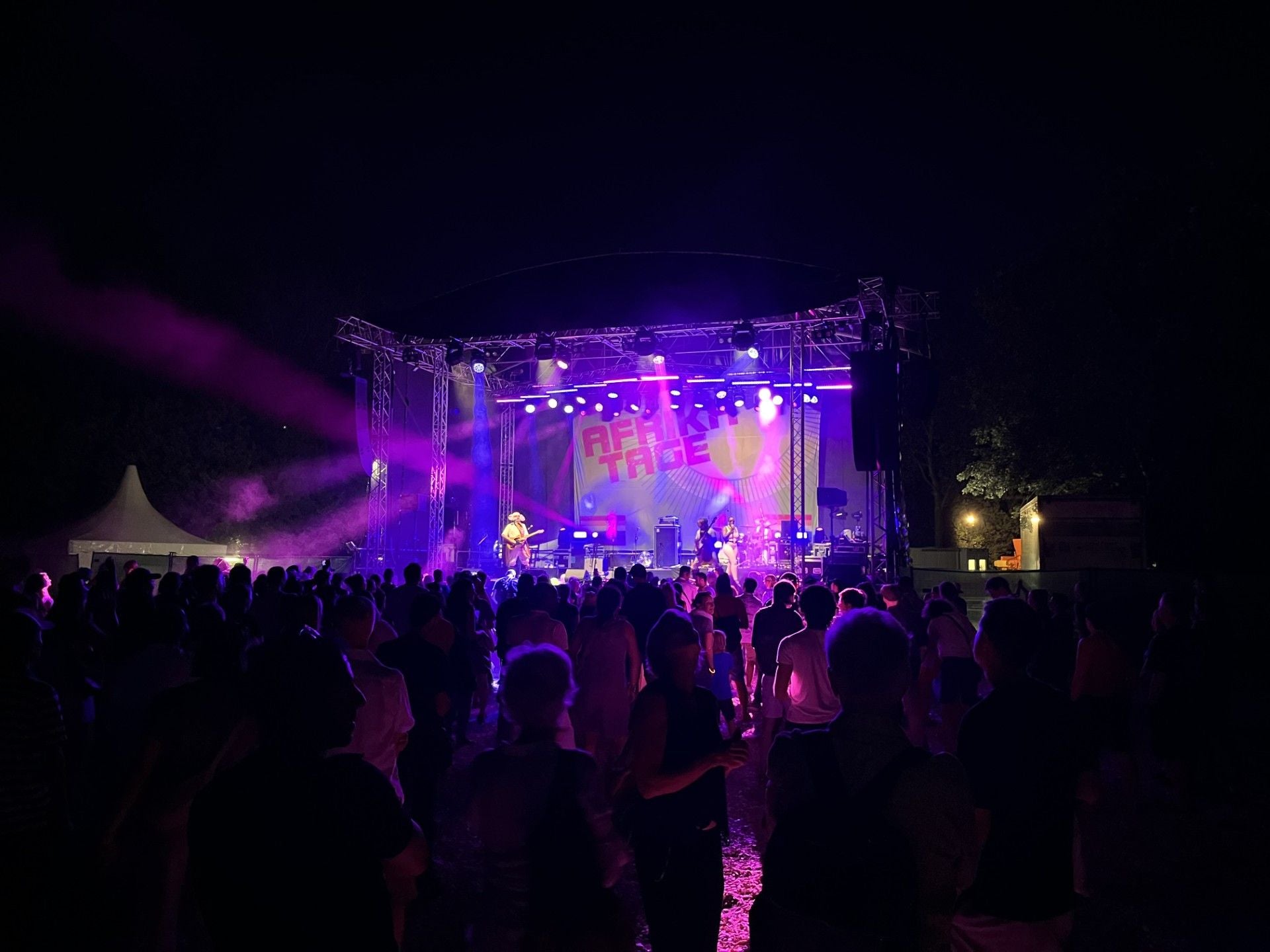 Viele Menschen stehen vor einer bunt beleuchteten Bühne bei einem Afrika Tage Festival.