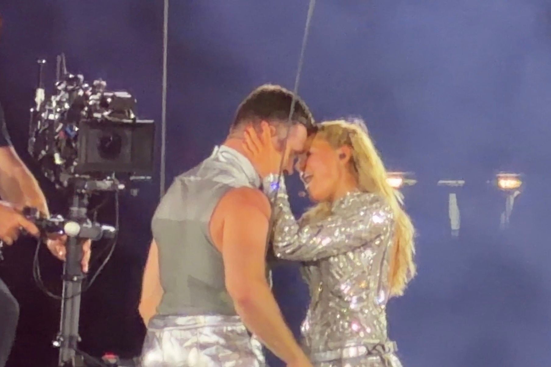 Helene Fischer berührt sanft das Gesicht eines Tänzers auf der Bühne, beide tragen silberne Outfits.