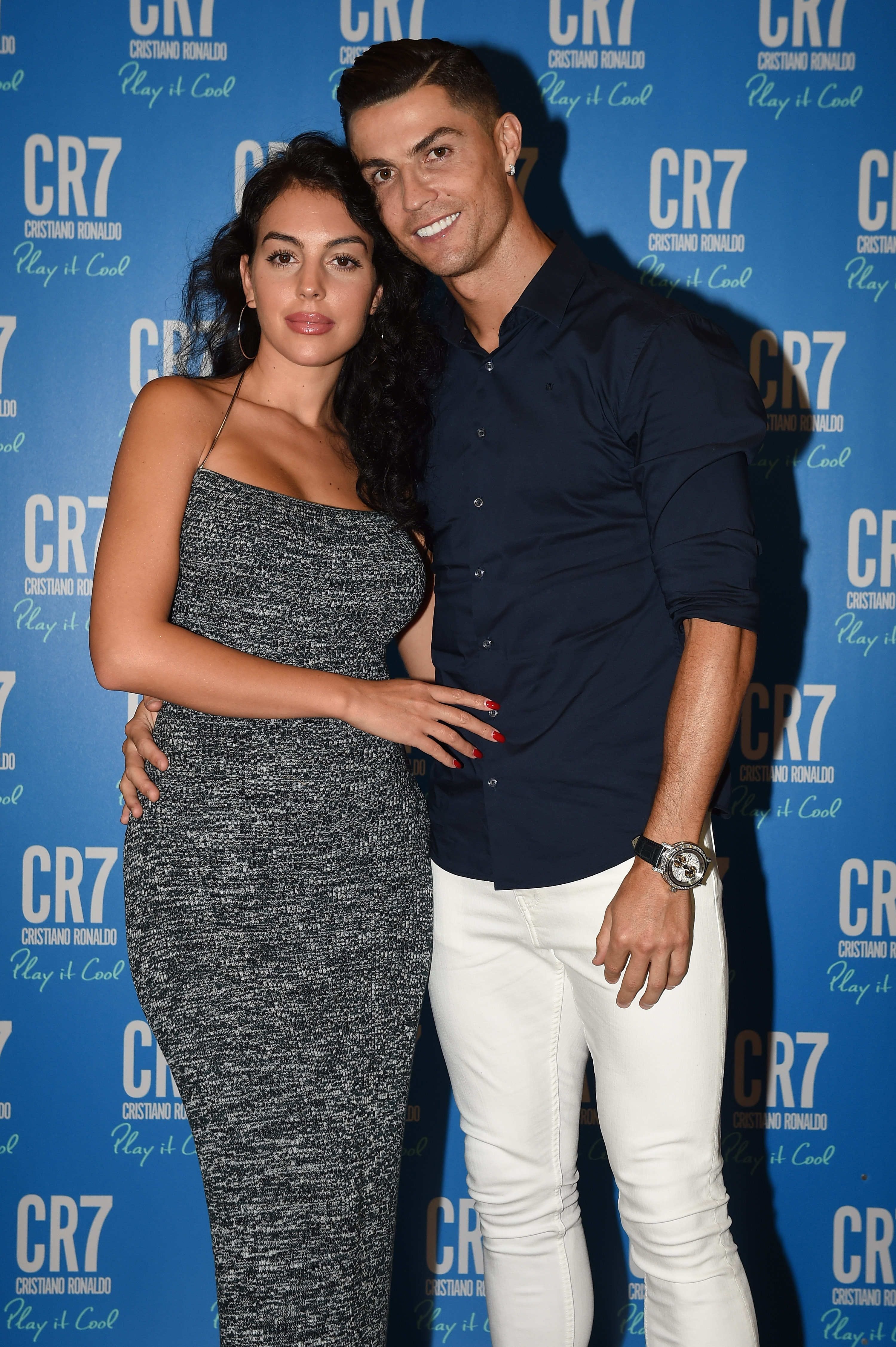 Ein Mann und eine Frau posieren gemeinsam vor einer blauen CR7-Presserückwand.