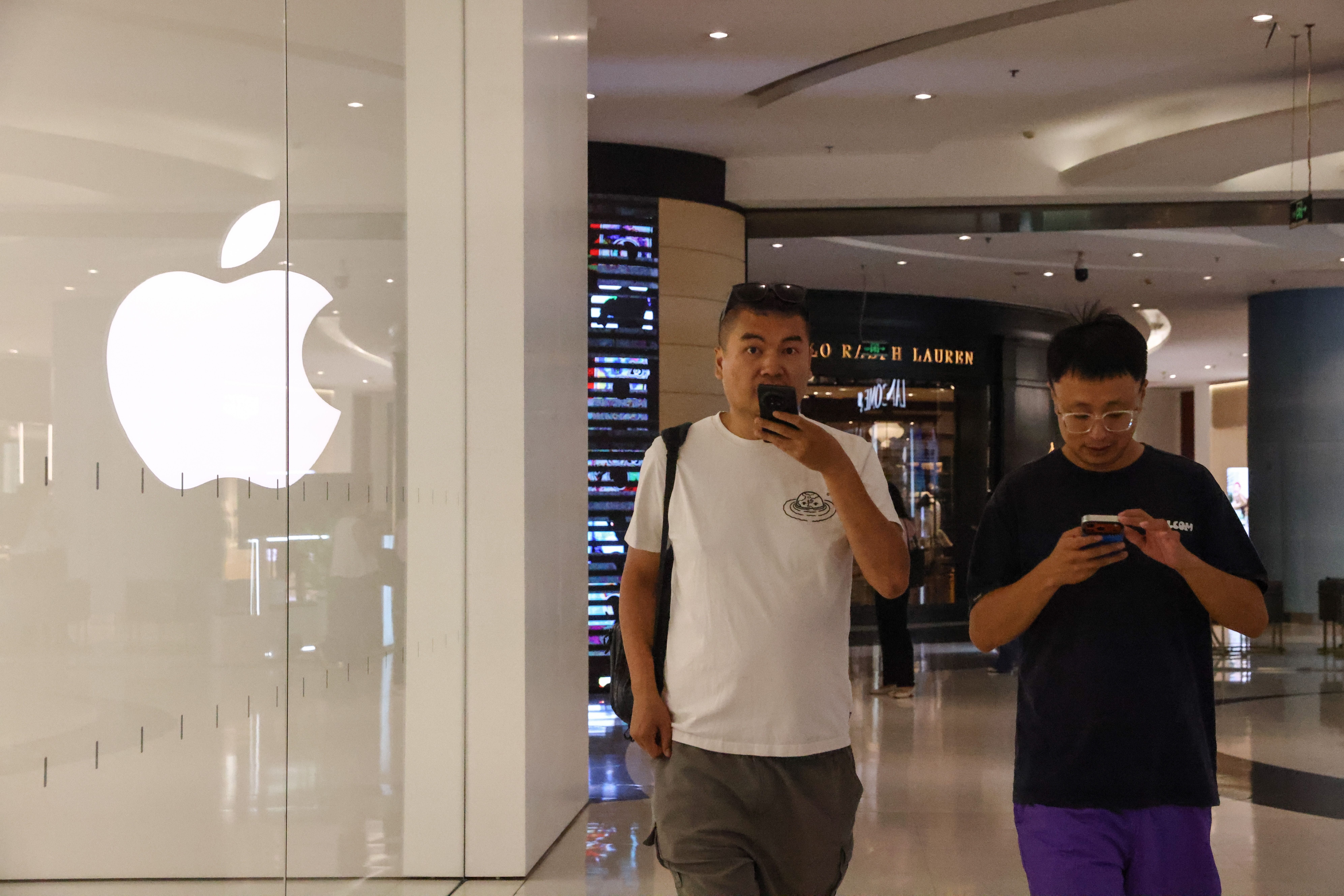 Zwei Männer gehen an einem Apple Store in einem Einkaufszentrum in Peking vorbei.