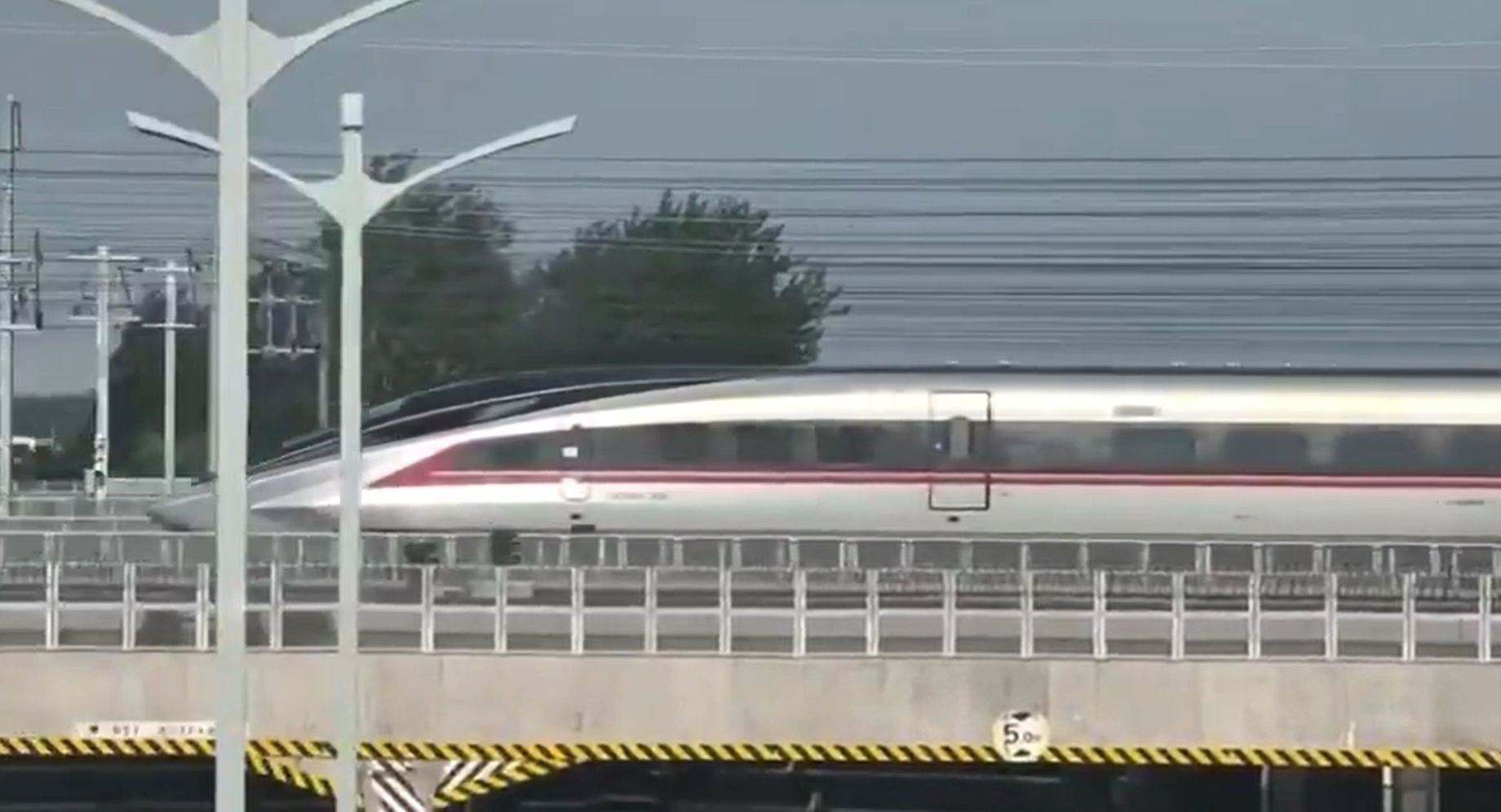Ein moderner Hochgeschwindigkeitszug fährt auf einer erhöhten Bahnstrecke in China.