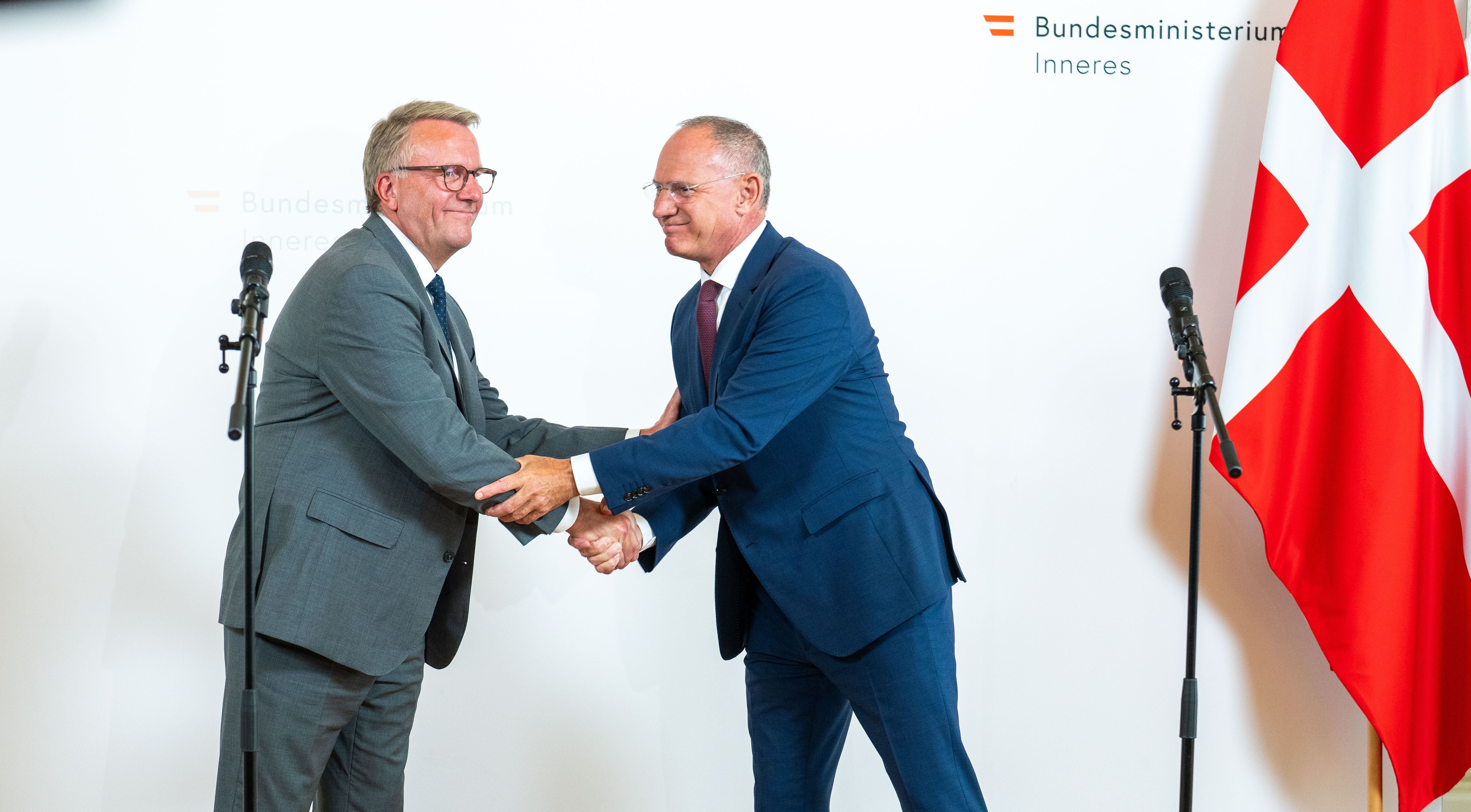 Zwei Männer im Anzug geben sich bei einer Pressekonferenz in Wien die Hand.
