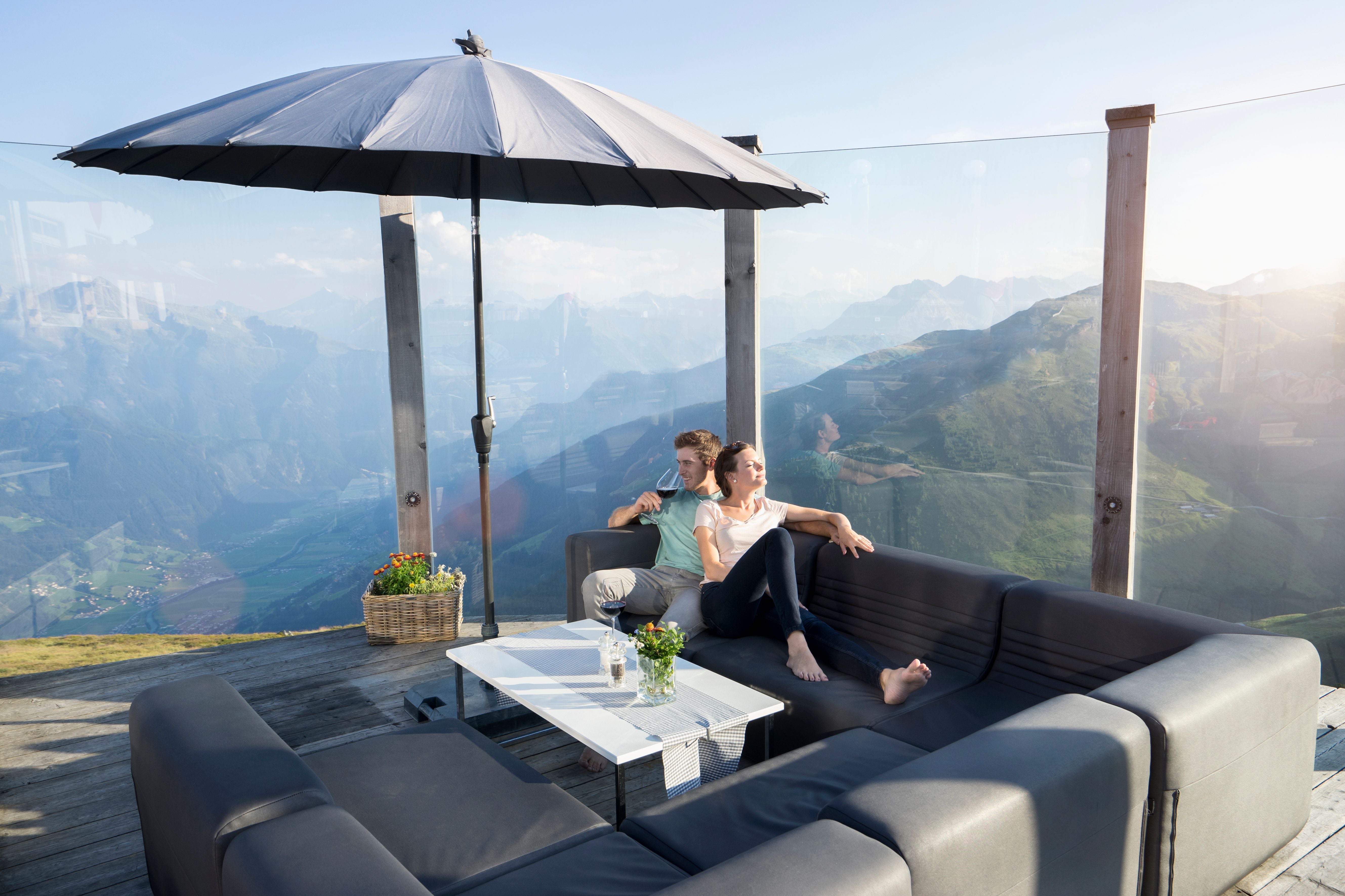 Ein Paar entspannt auf einer Terrasse mit Panoramablick über die Berge im Zillertal, Tirol.