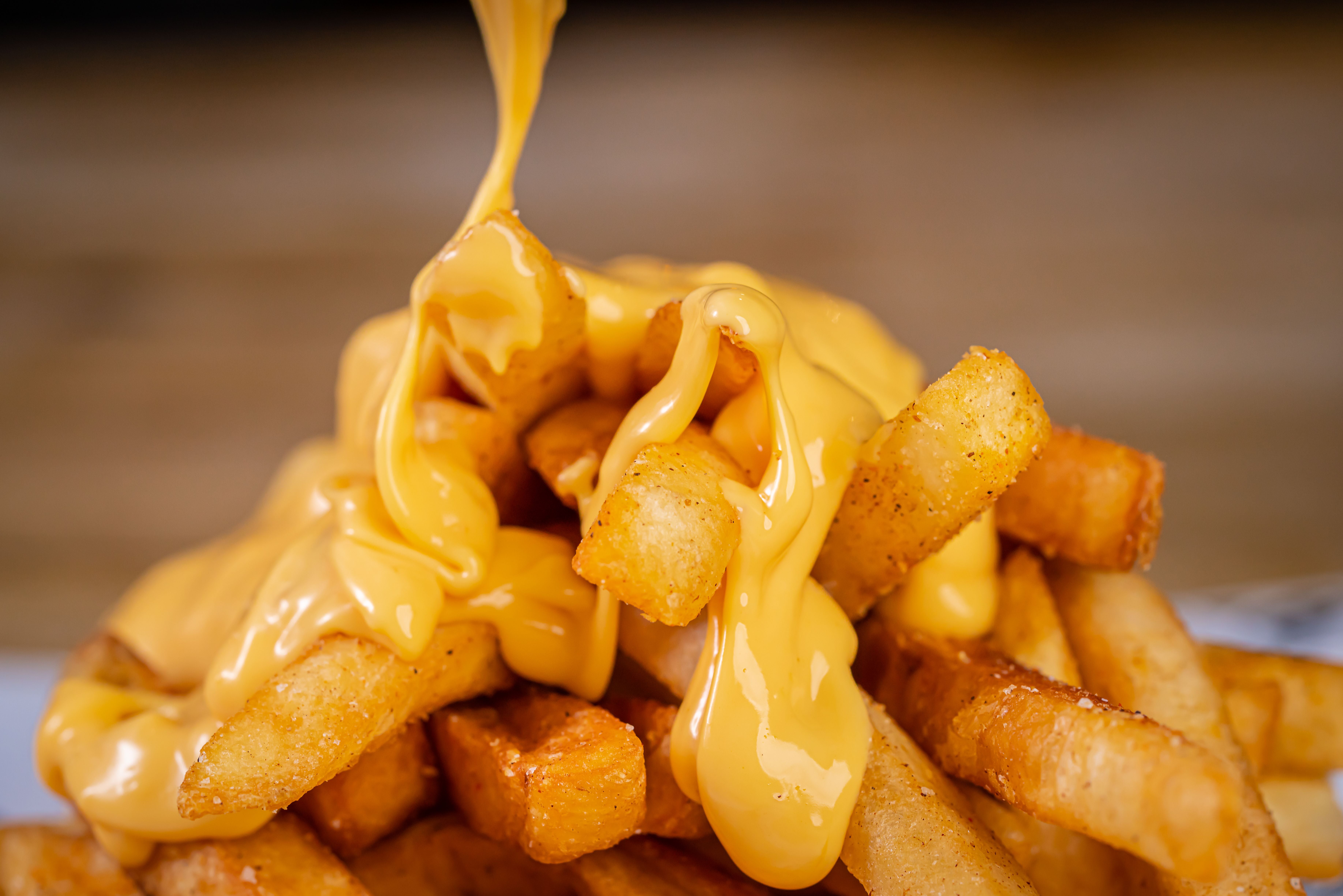 Pommes frites werden mit geschmolzenem Käse übergossen.