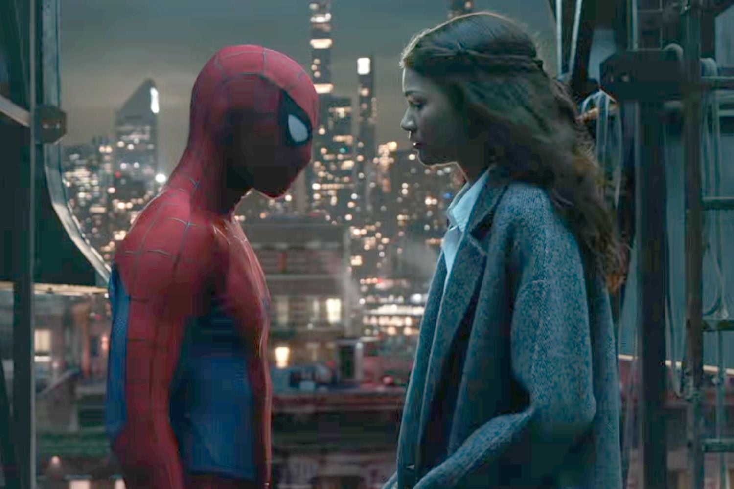 Spider-Man und eine Frau stehen sich bei Nacht mit Stadtlichtern im Hintergrund gegenüber.