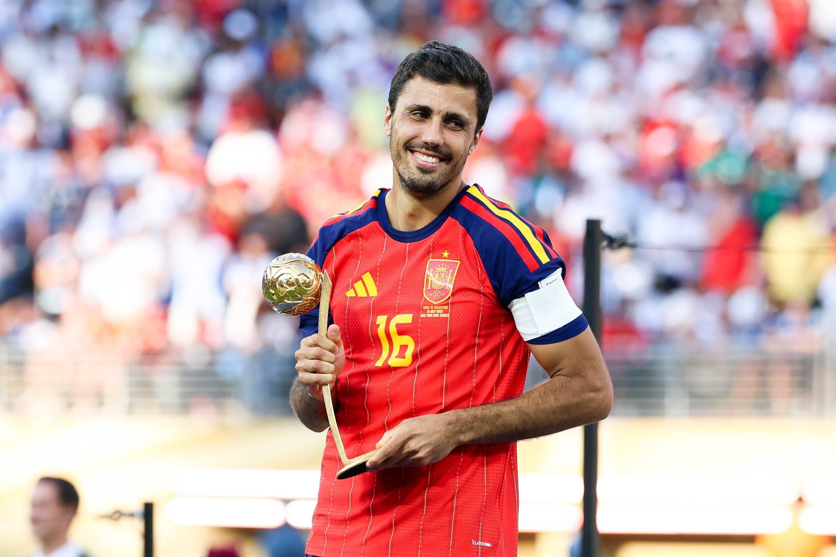 Ein spanischer Fußballspieler im roten Trikot hält den Goldenen Ball als bester Spieler des Turniers.