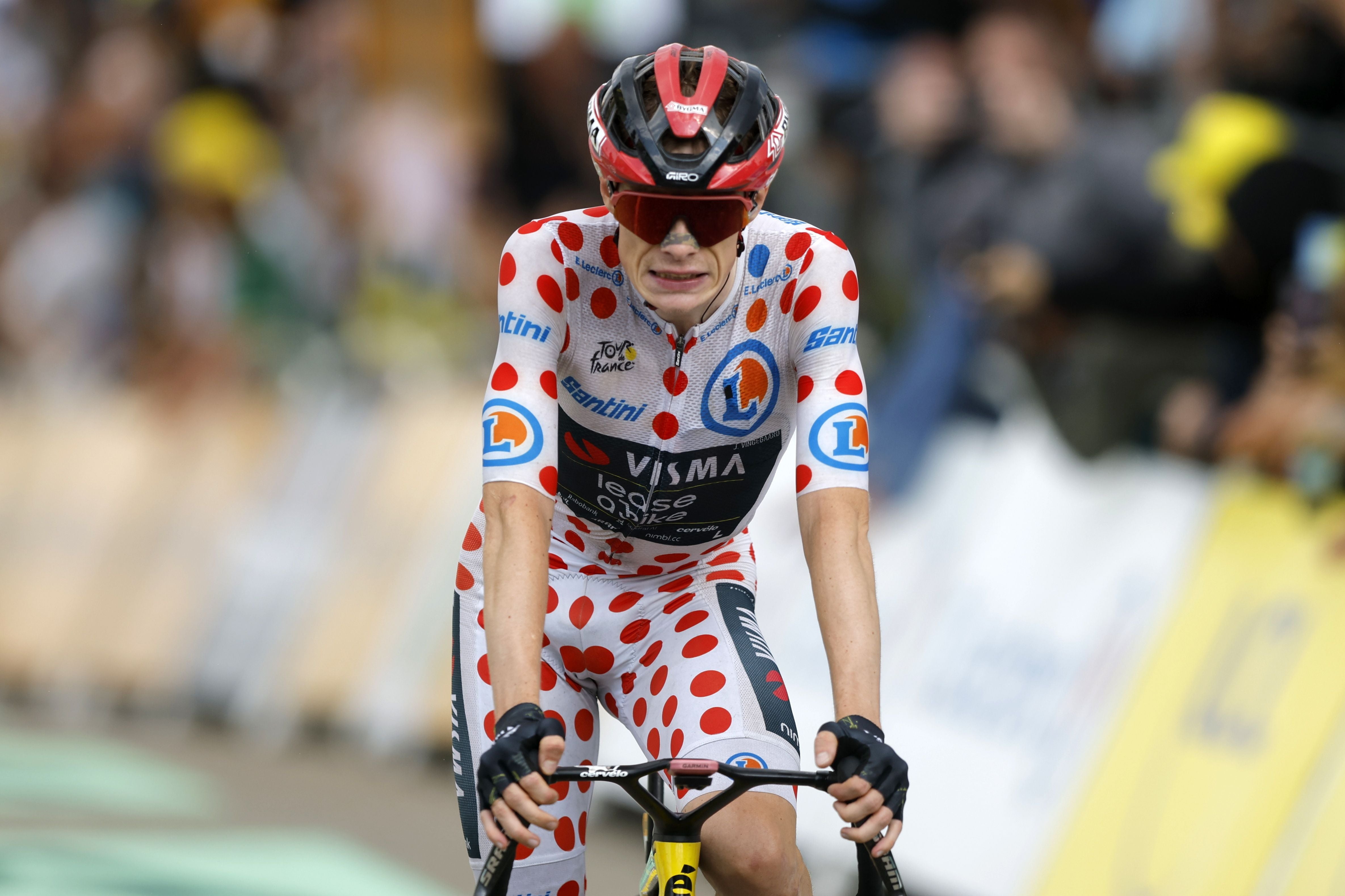 Radfahrer im gepunkteten Trikot erreicht das Ziel bei der Tour de France, Zuschauer im Hintergrund.
