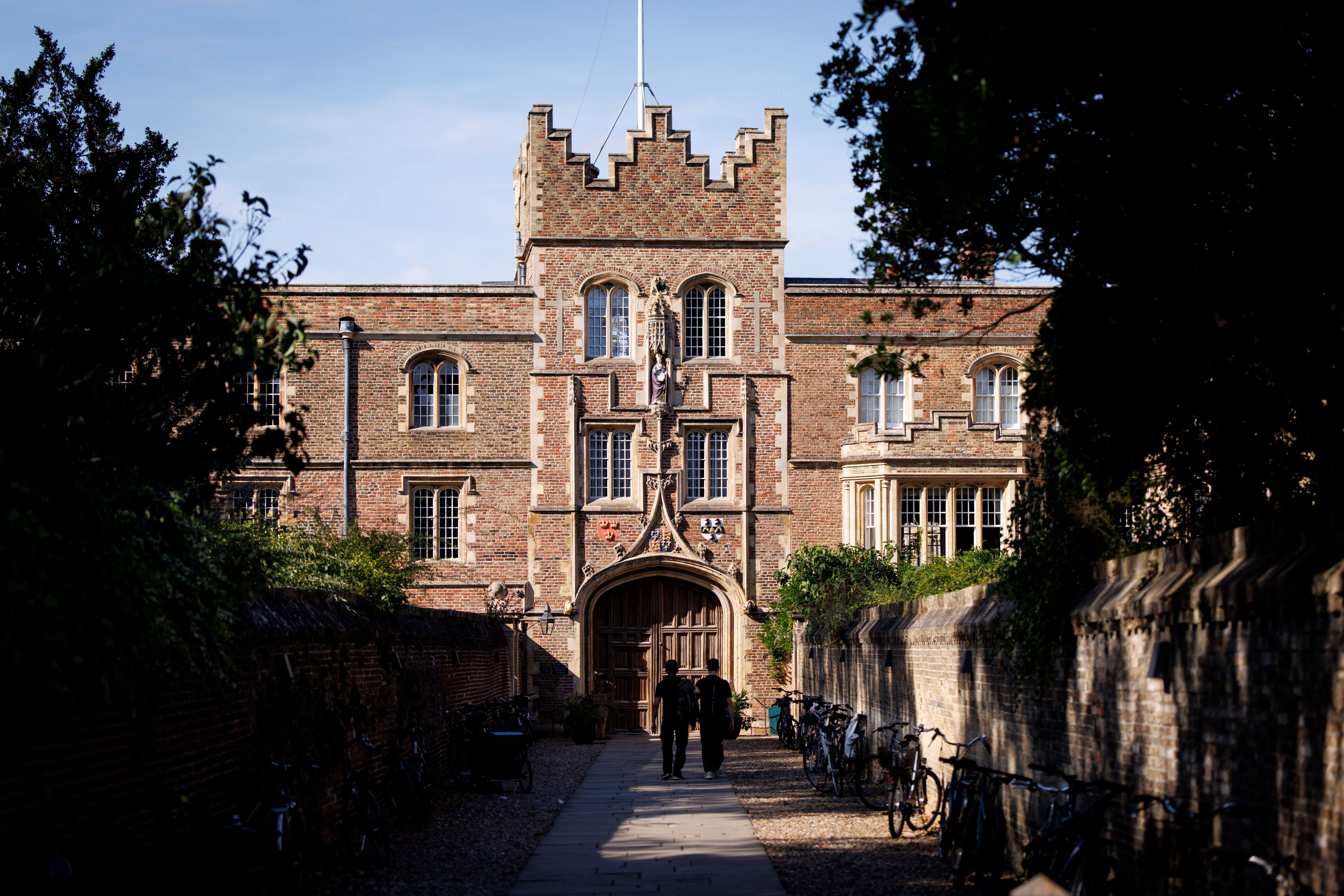 Zwei Personen gehen auf einen Eingang von Jesus College in Cambridge mit Fahrrädern an den Seiten zu.